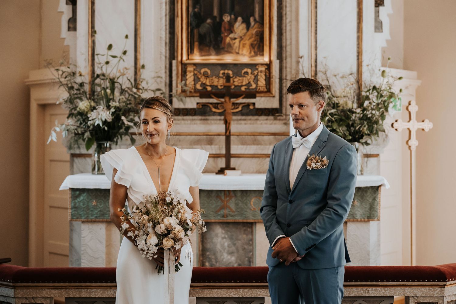 Wedding couple shares an emotional first look moment in an elegant white church interior.