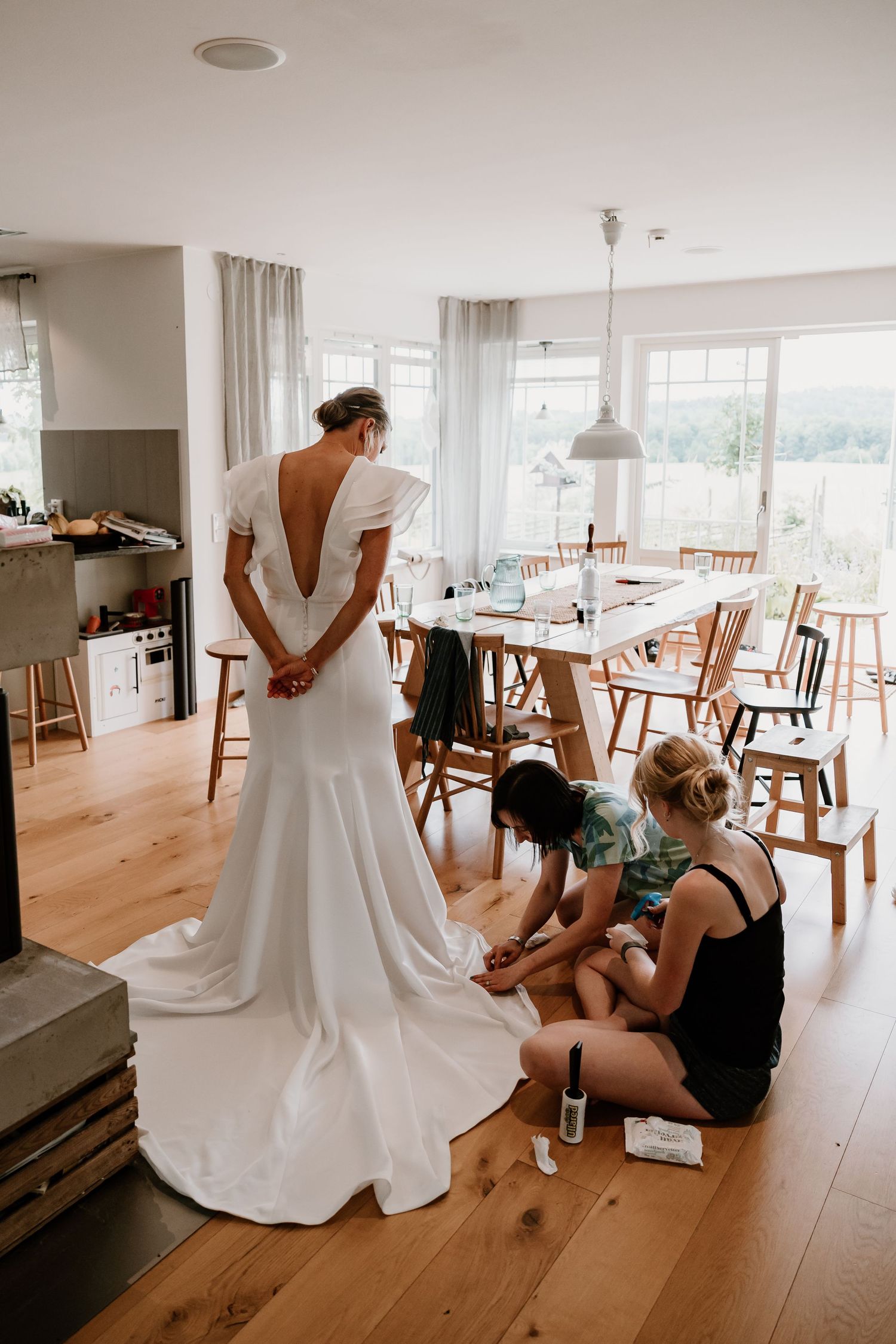 A wedding dress preparation sequence showing final adjustments being made in an elegant room with wooden floors and natural light.