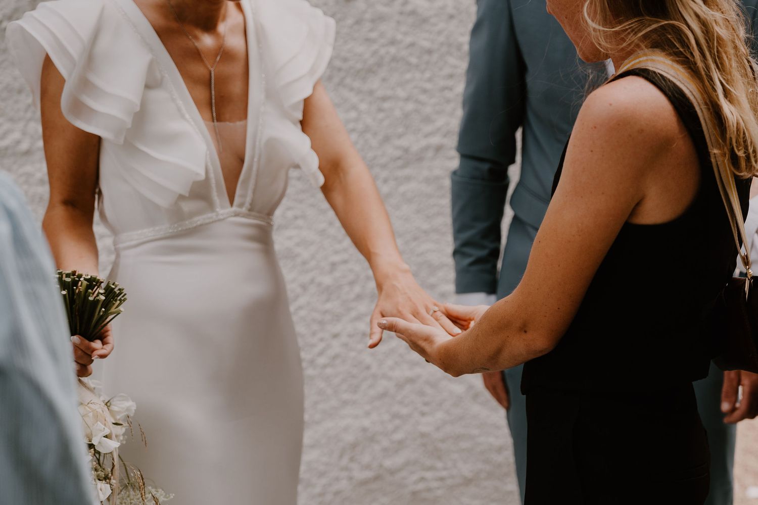 A row of people in wedding attire gather during an outdoor celebration at sunset.