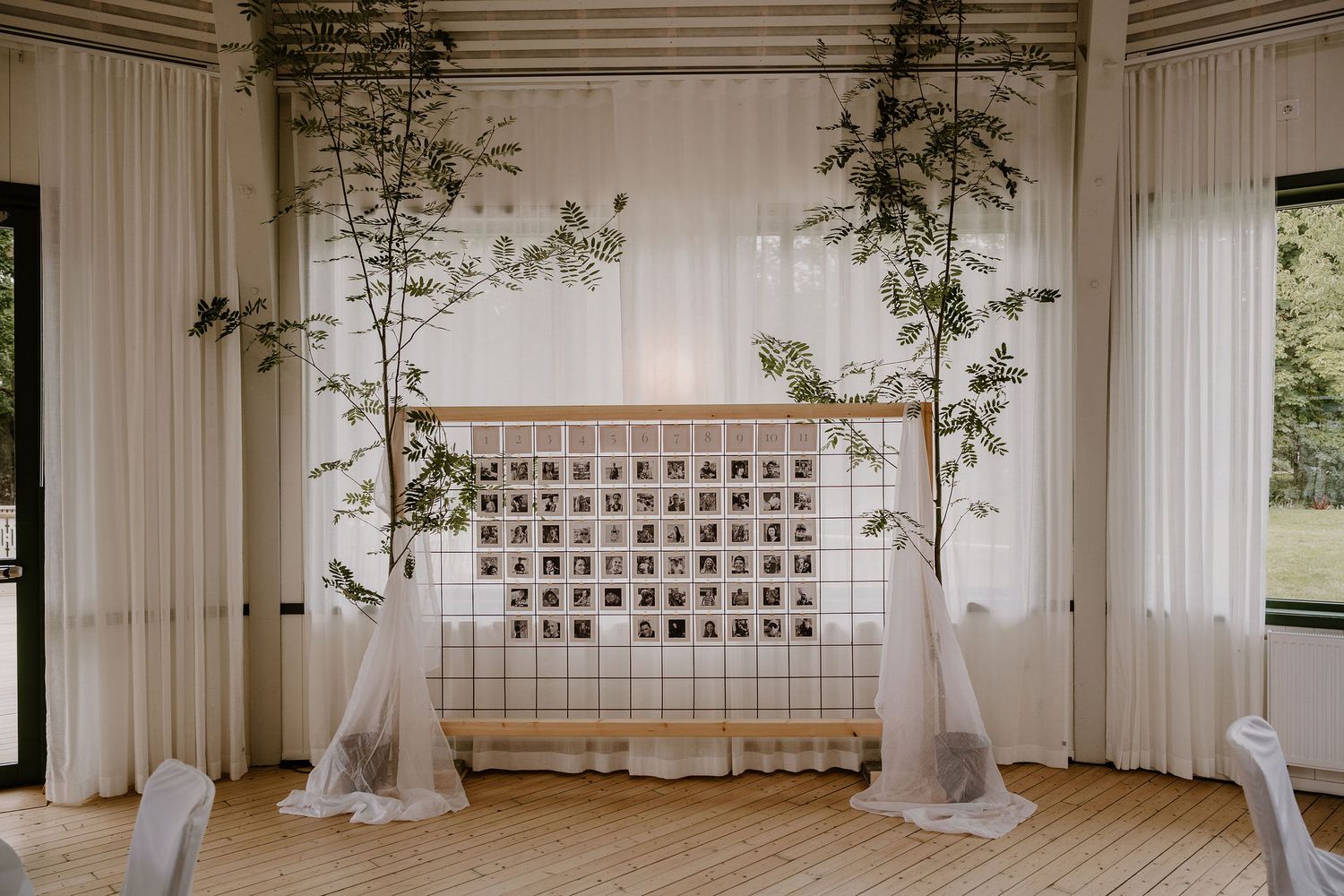 White fabric draped columns line an indoor venue space with ornate lattice windows and white decor details.