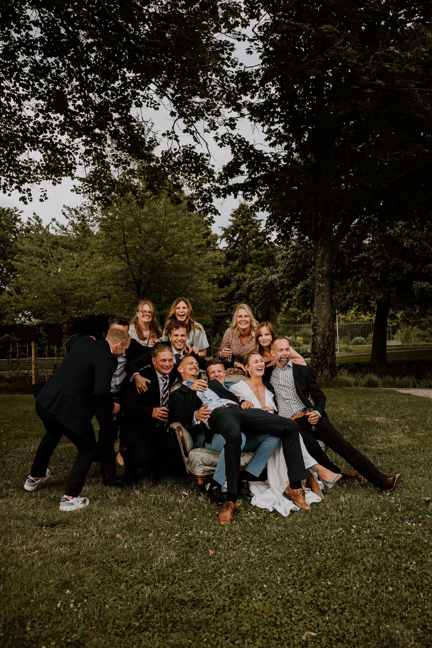 A group poses together for a casual outdoor photo in a park setting with trees in the background.