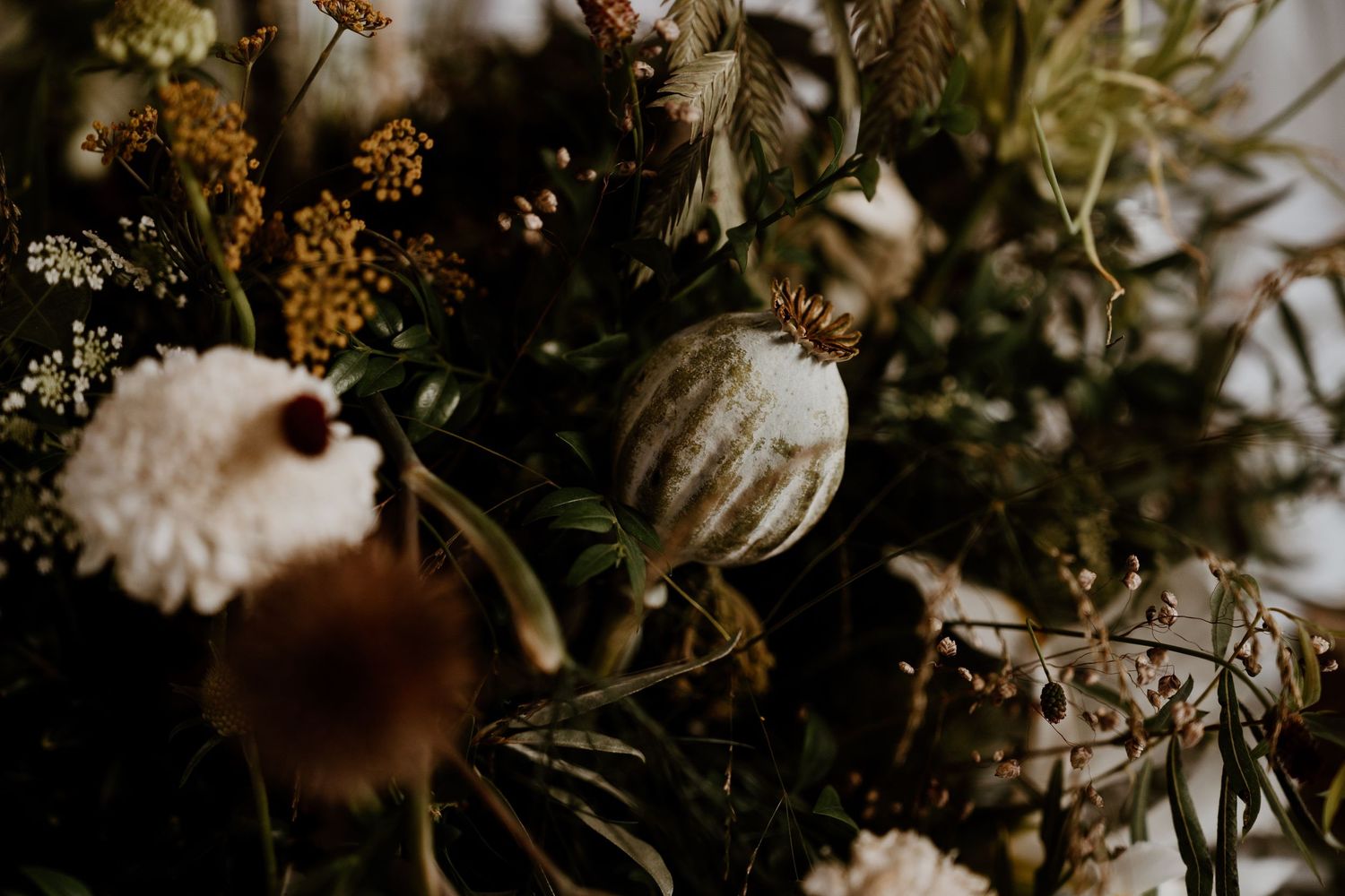 Close-up view of moody Christmas decorations with dark gold and white ornaments and flowers in vintage style.