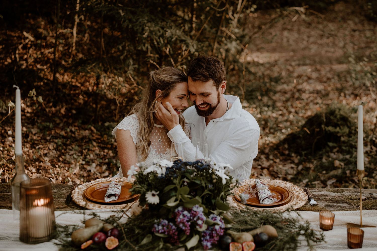 A romantic outdoor dining scene with elegant table settings, rustic decor and floral centerpieces at sunset.
