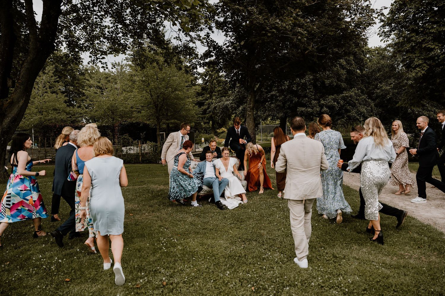 Wedding guests gather on a lush green lawn during an outdoor summer celebration.