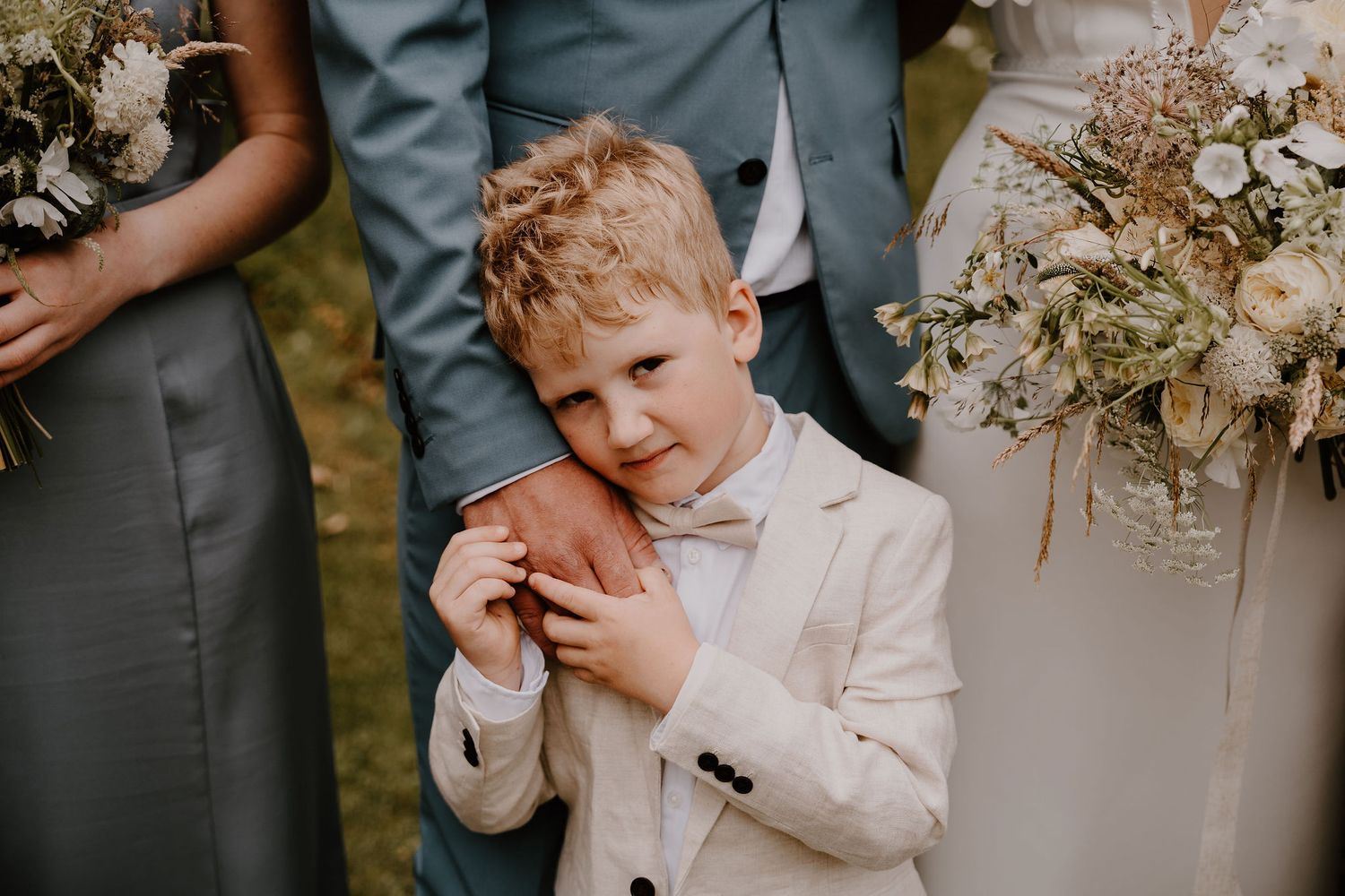 A collage of candid wedding moments with the ring bearer and guests in gray and white formal attire.
