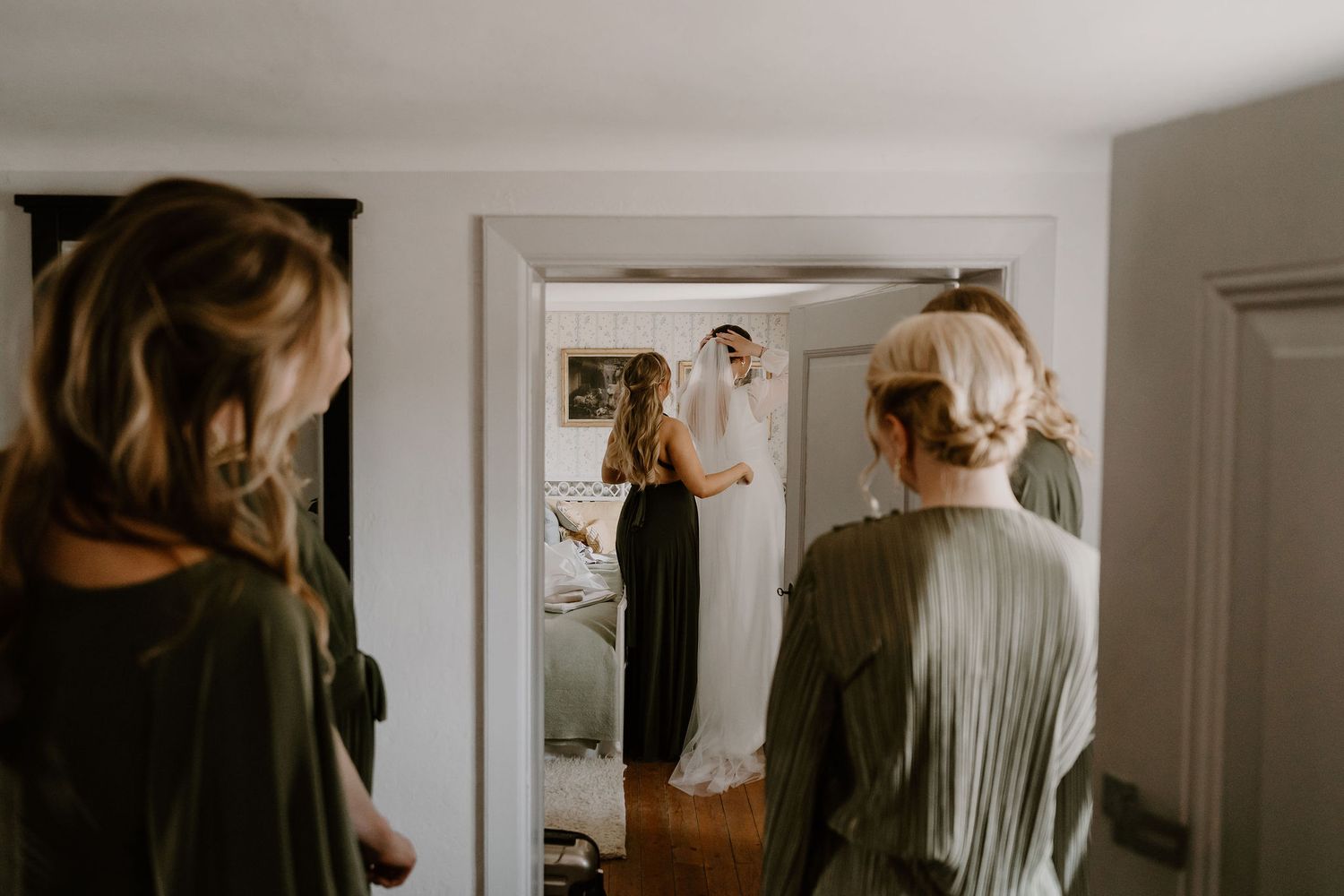 A candid warm-toned shot of someone standing in front of a mirror with others reflecting in the background.