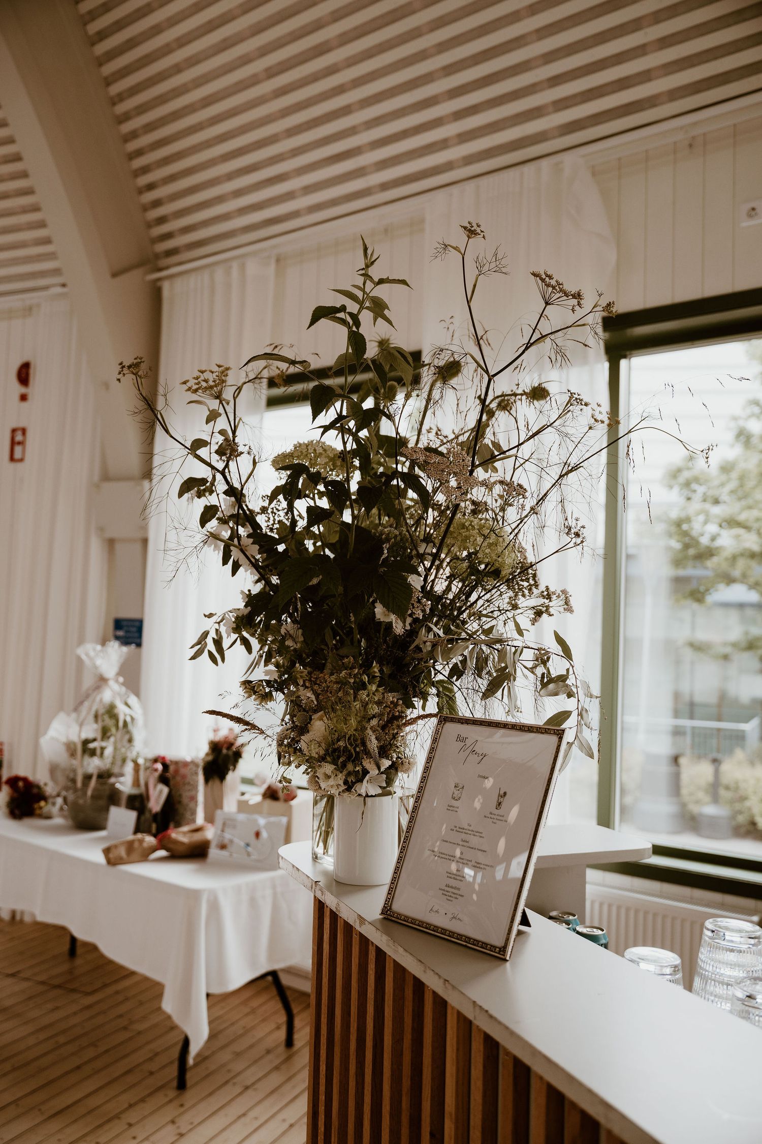 Minimalist windowsill decor featuring potted plants and dried flowers in white vases against a bright interior setting.