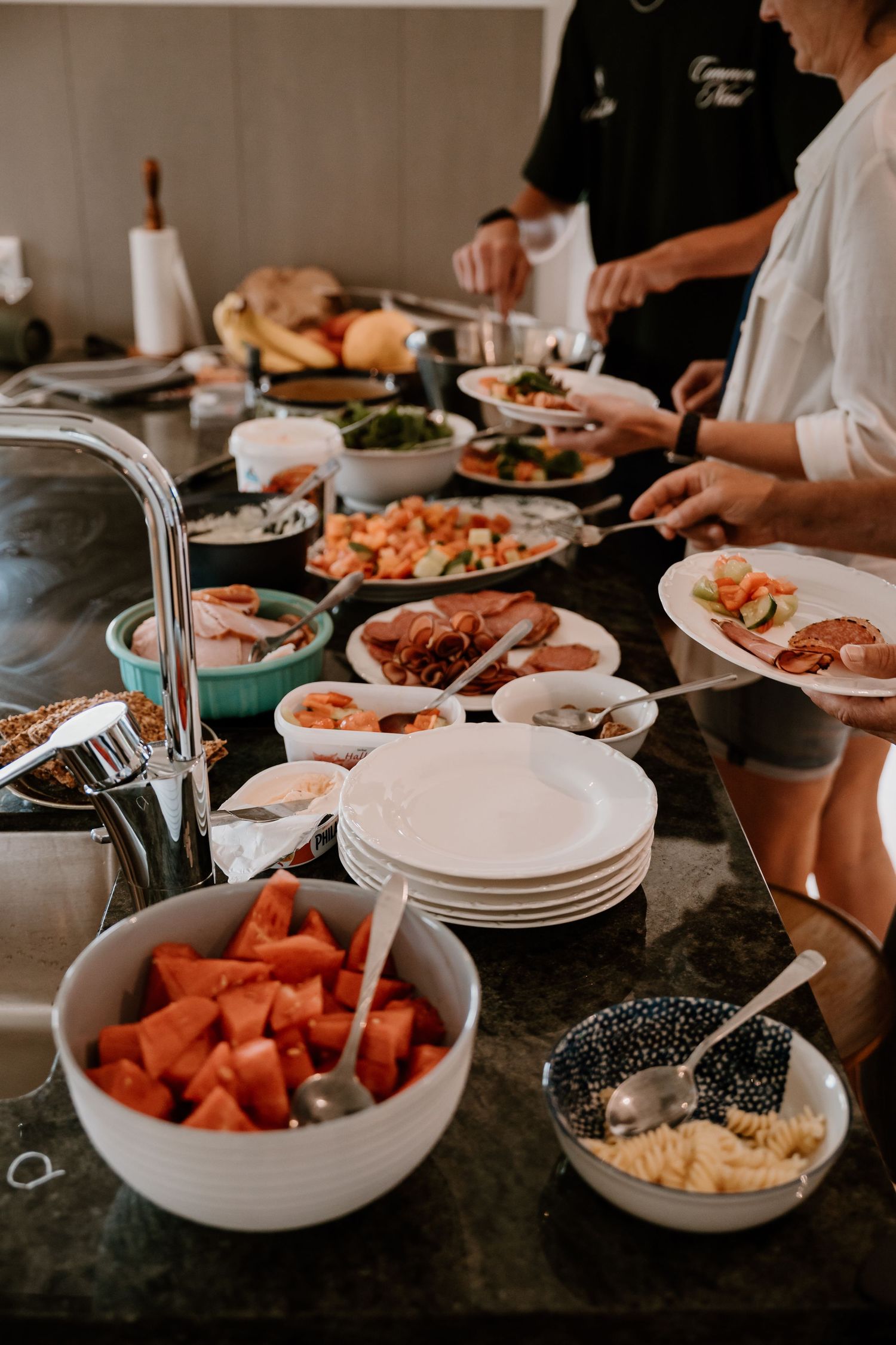 Fresh ingredients and prepared food items displayed on white plates at a casual dining gathering.