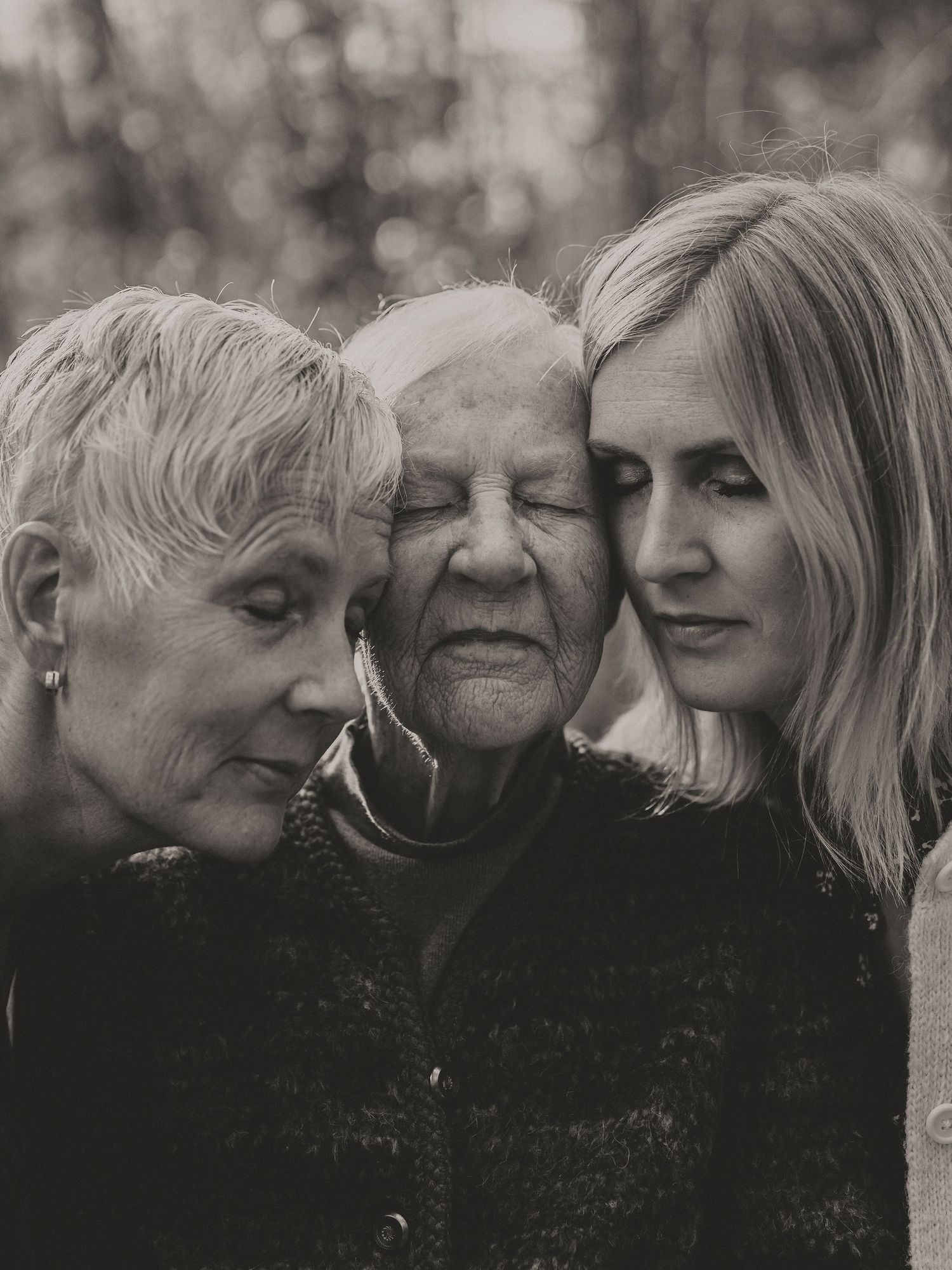 Black and white portrait of three generations posed closely together in an intimate family moment.