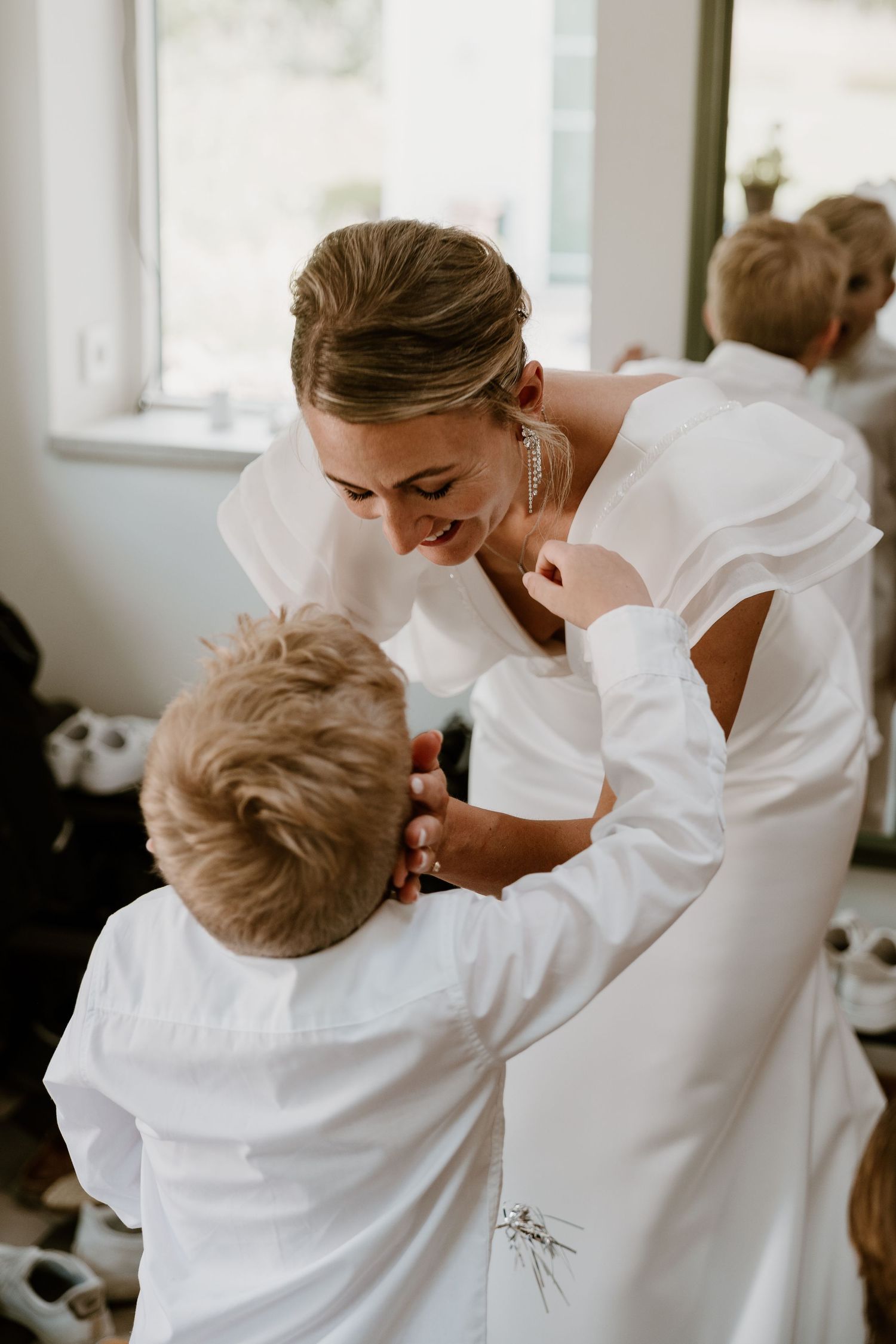 A tender moment captured between mother and child both wearing white, embracing in an intimate series.