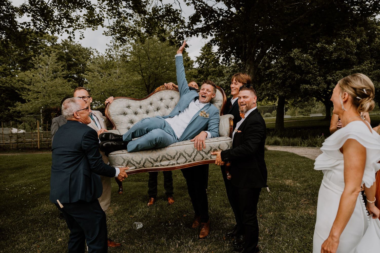 A celebratory group photo during a wedding ceremony in a scenic outdoor park setting.