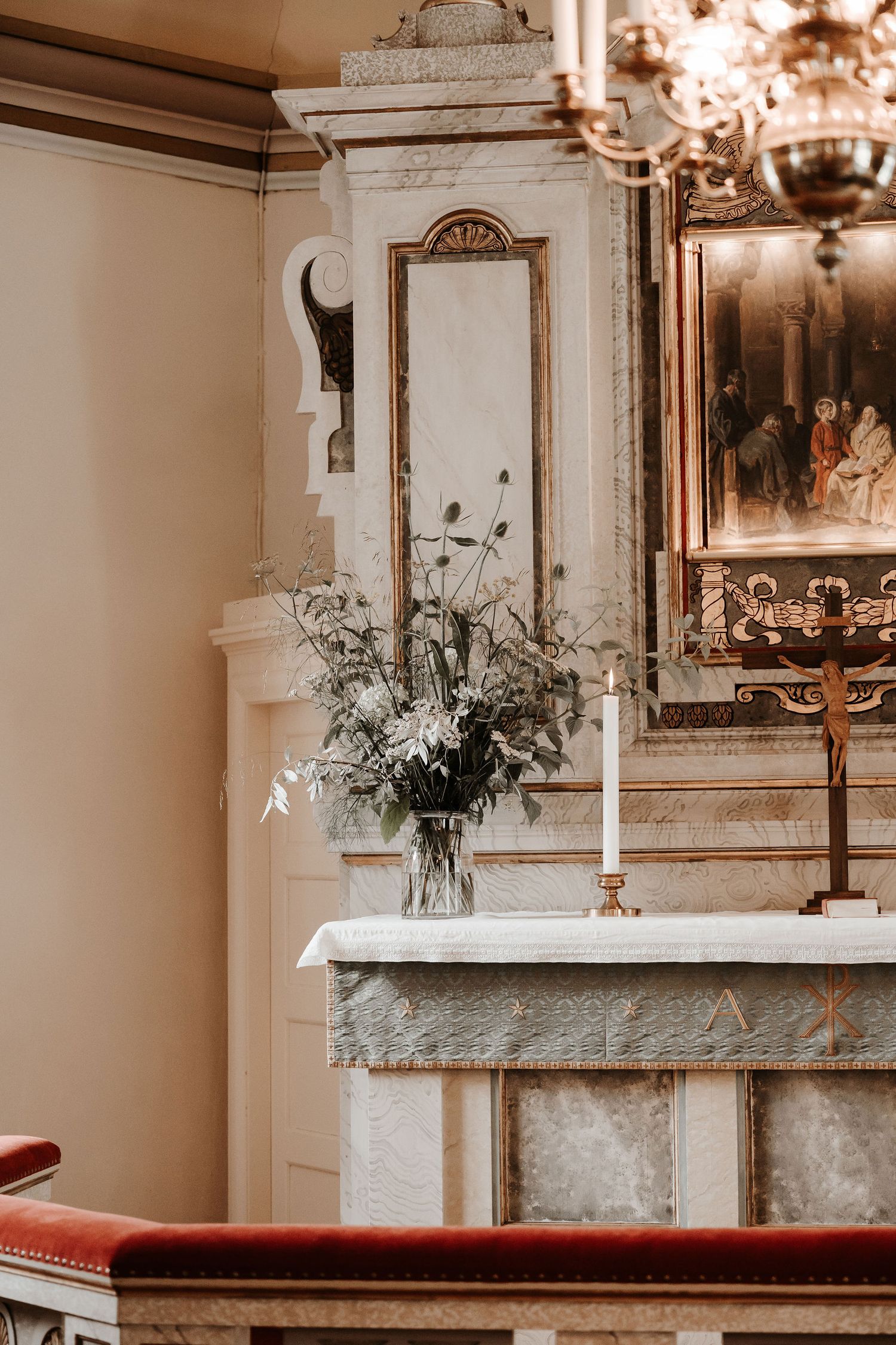 Elegant white altar decorated with fresh greenery and candles in historic church interior setting.