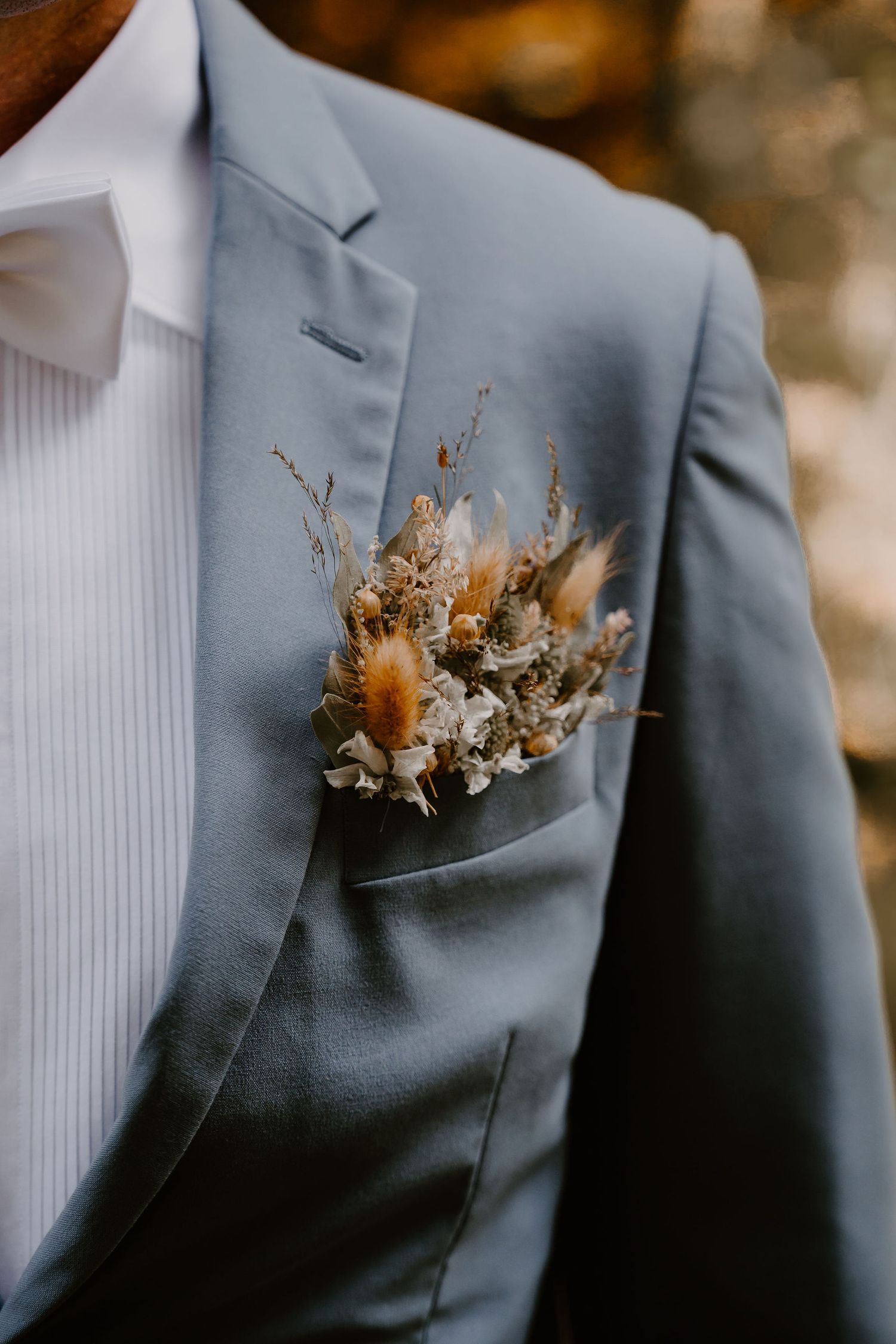 Close-up details of a dried floral boutonniere on a gray suit jacket lapel shown from different angles and distances.