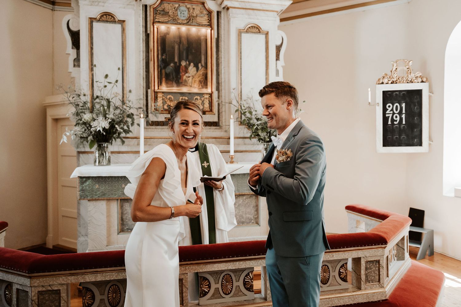 Bride and groom exchange loving looks inside traditional chapel with ornate decor.