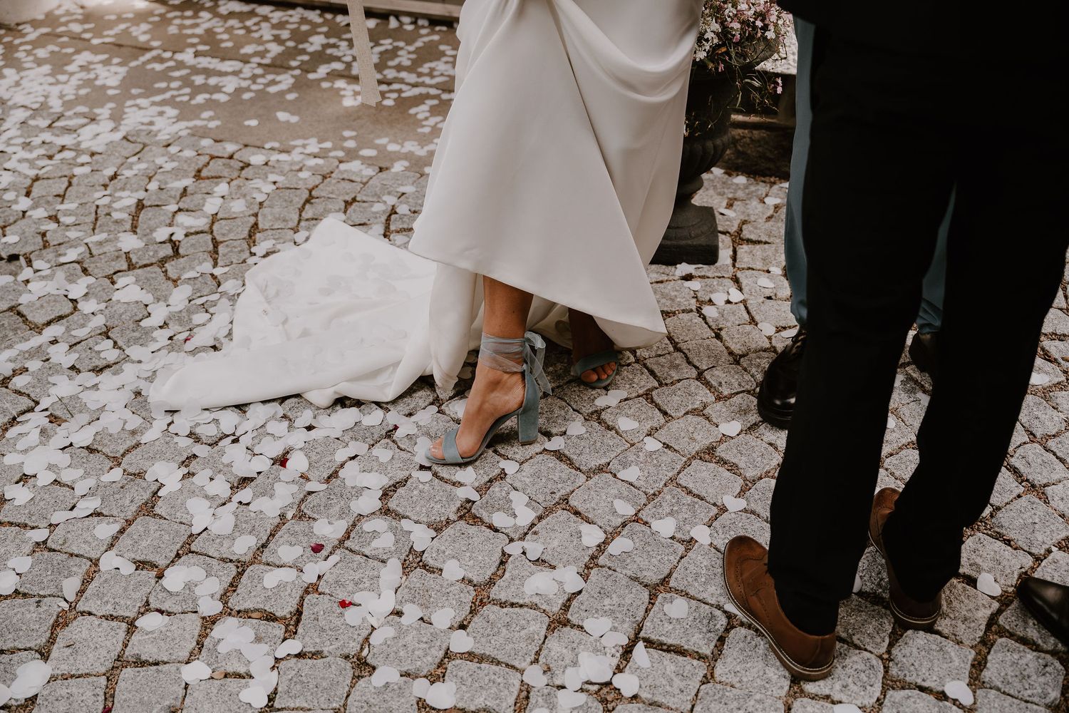 Several cropped photos showcase feet walking on stone cobblestones during a wedding celebration.