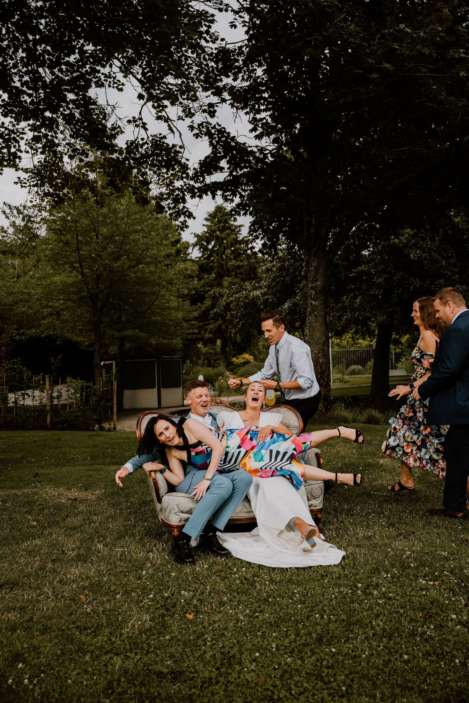 Family relaxing together on grass in park during warm sunny day creating candid lifestyle moments.