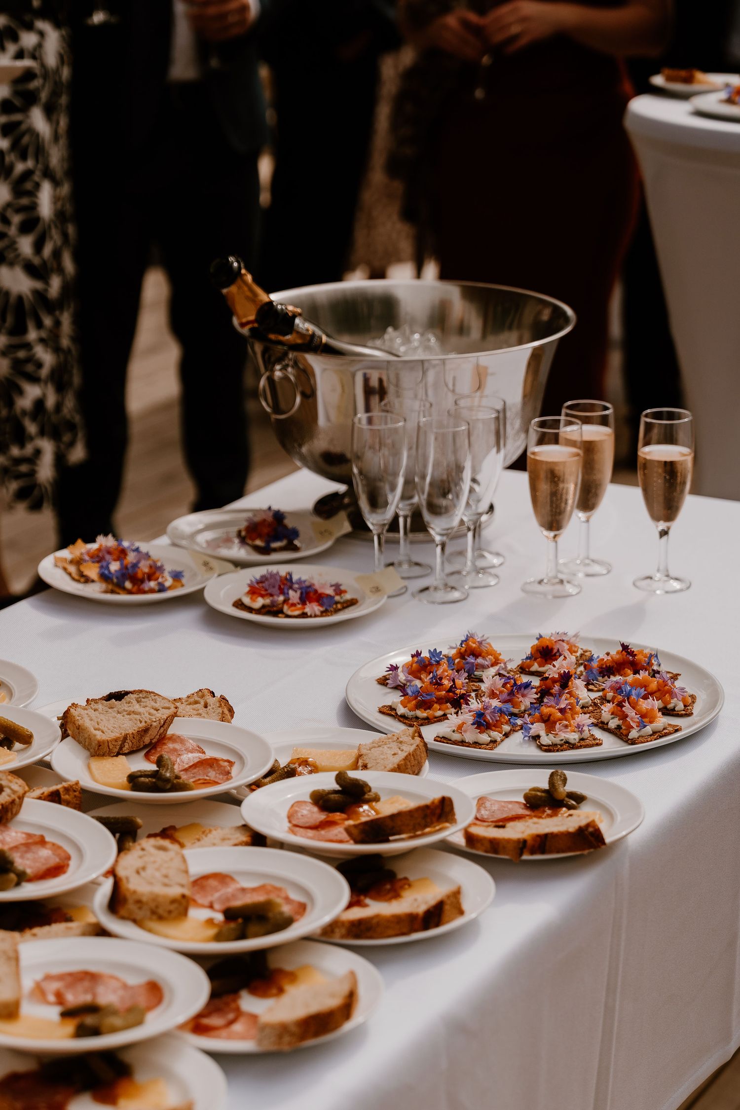 Elegantly plated appetizers and hors d'oeuvres on white plates line a formal dining table covered with a crisp white tablecloth.