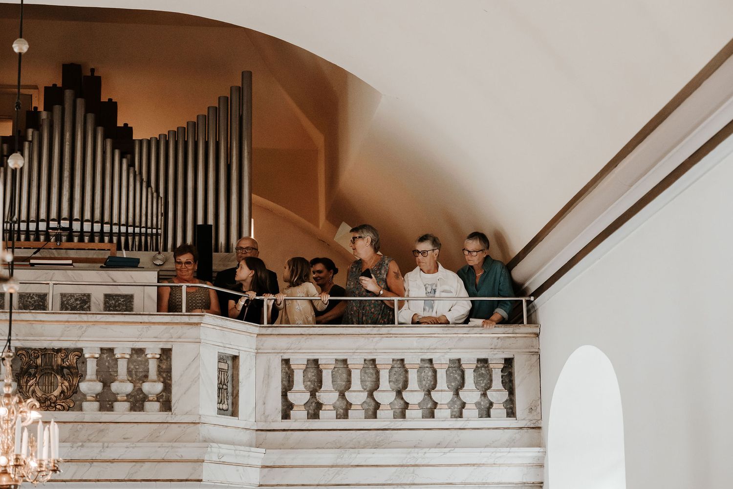 Classic church interior with organ pipes mounted above and wooden railings along the balcony during a wedding ceremony.