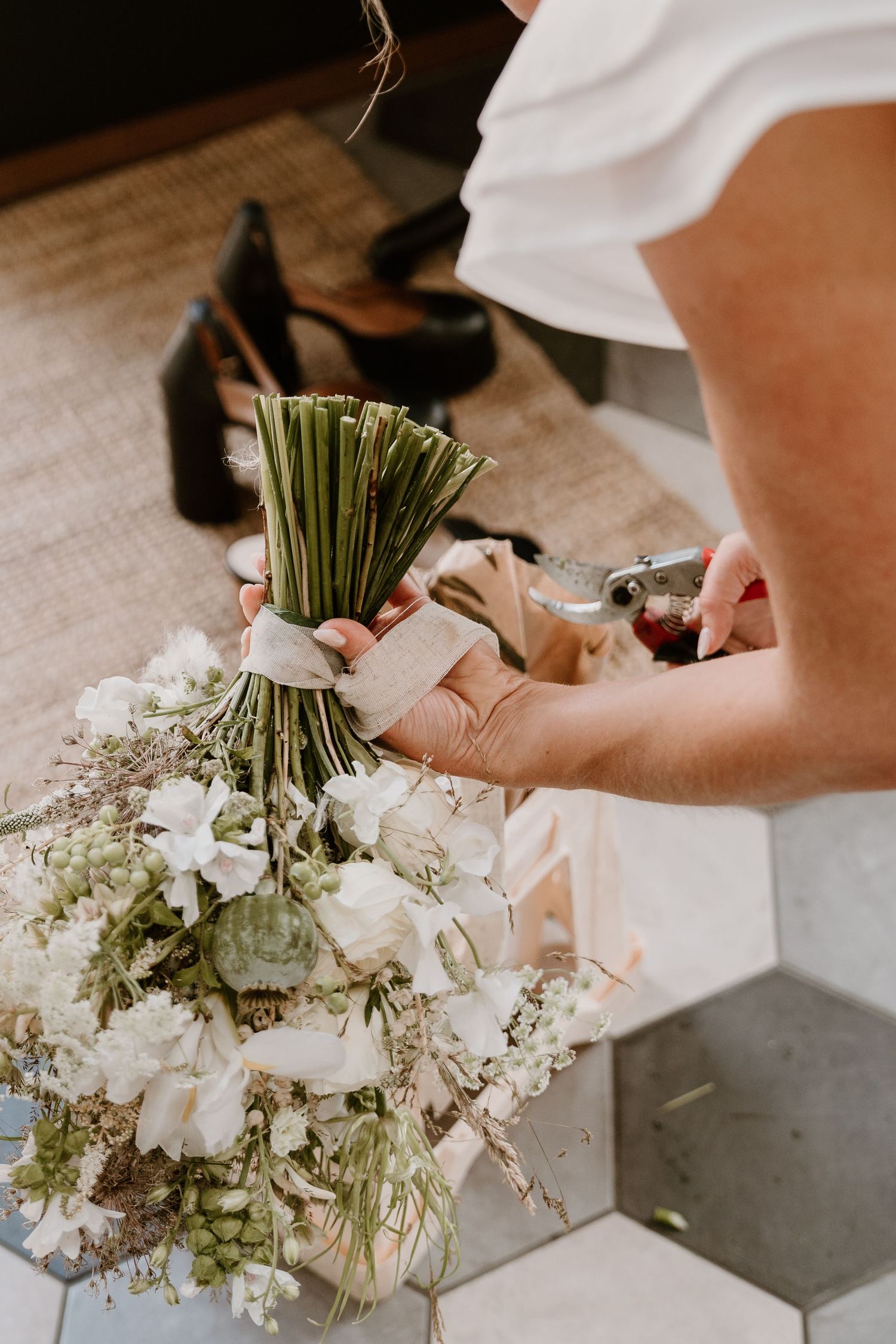 Close-up of delicate white floral bouquet with baby's breath being prepared on a textured surface.