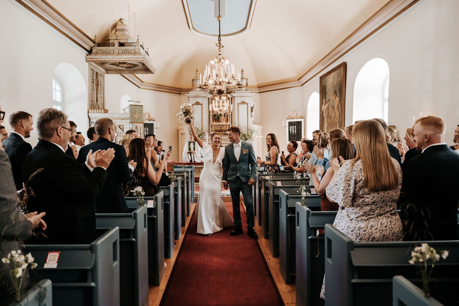 Wedding ceremony in progress inside historic church with guests seated in wooden pews.