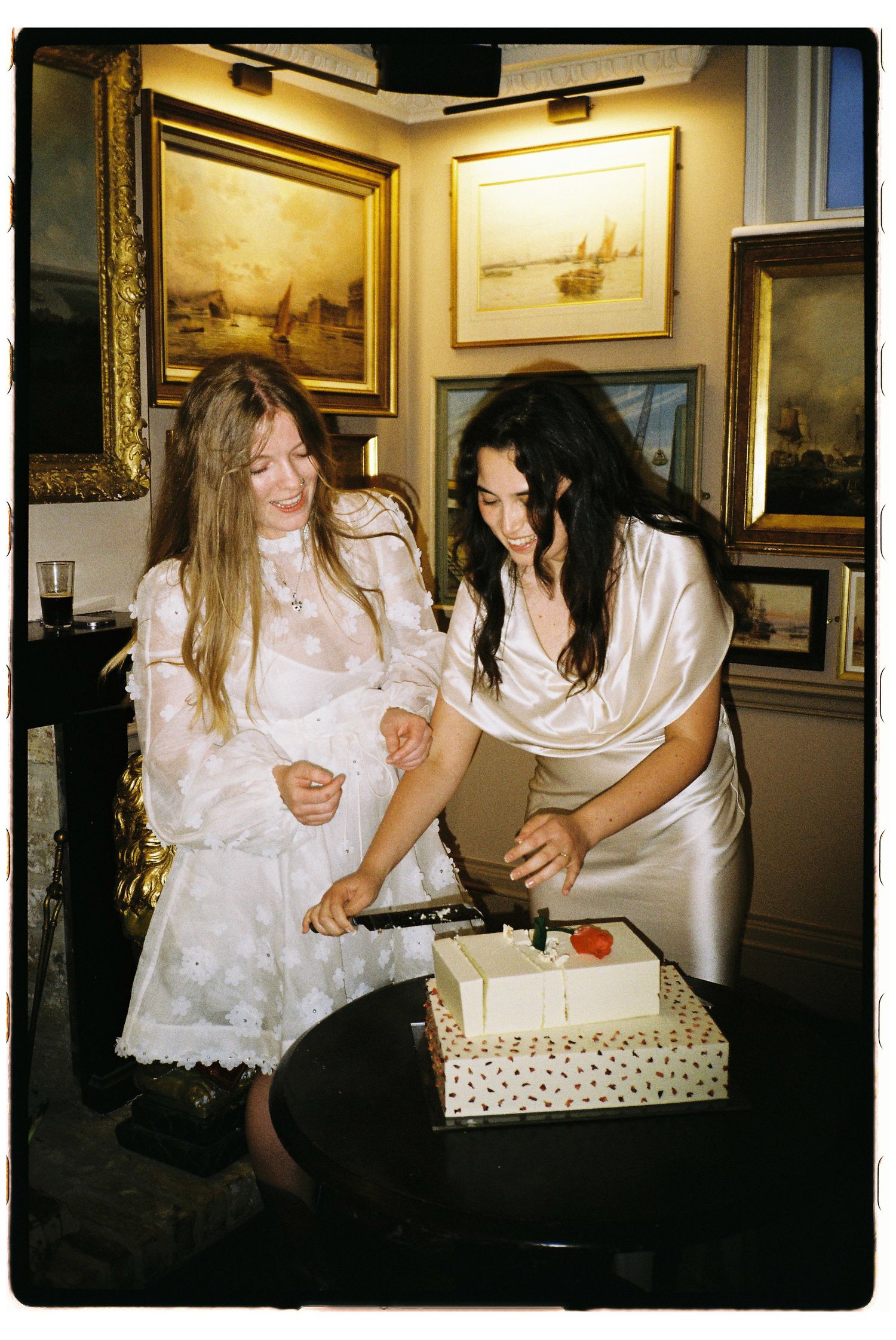 Three candid photos show friends in white dresses gathered around a table at what appears to be an art gallery or museum.