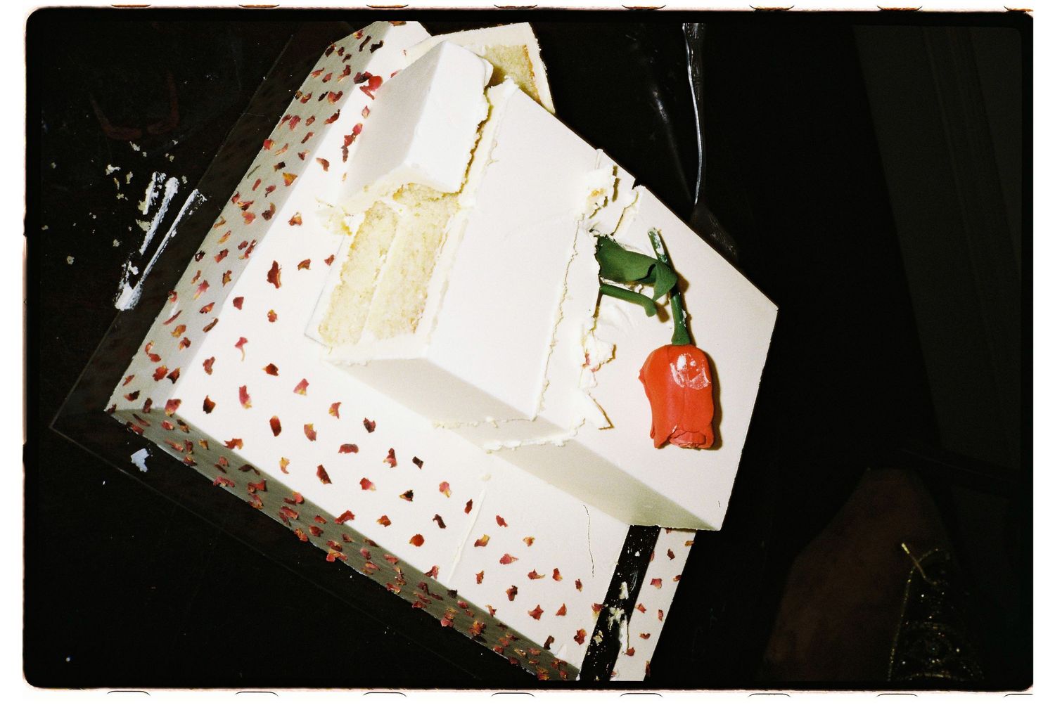 Small white gift box with red heart pattern sits against dark background, photographed from multiple angles.