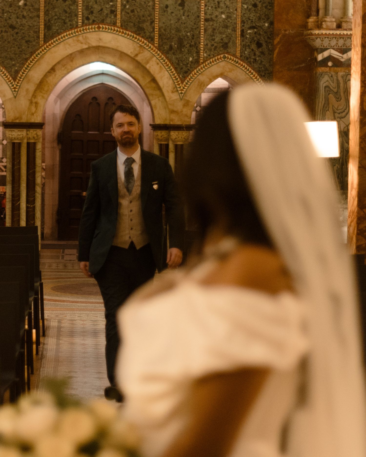 A wedding ceremony in a historic church with ornate arched doorways and decorative golden walls.