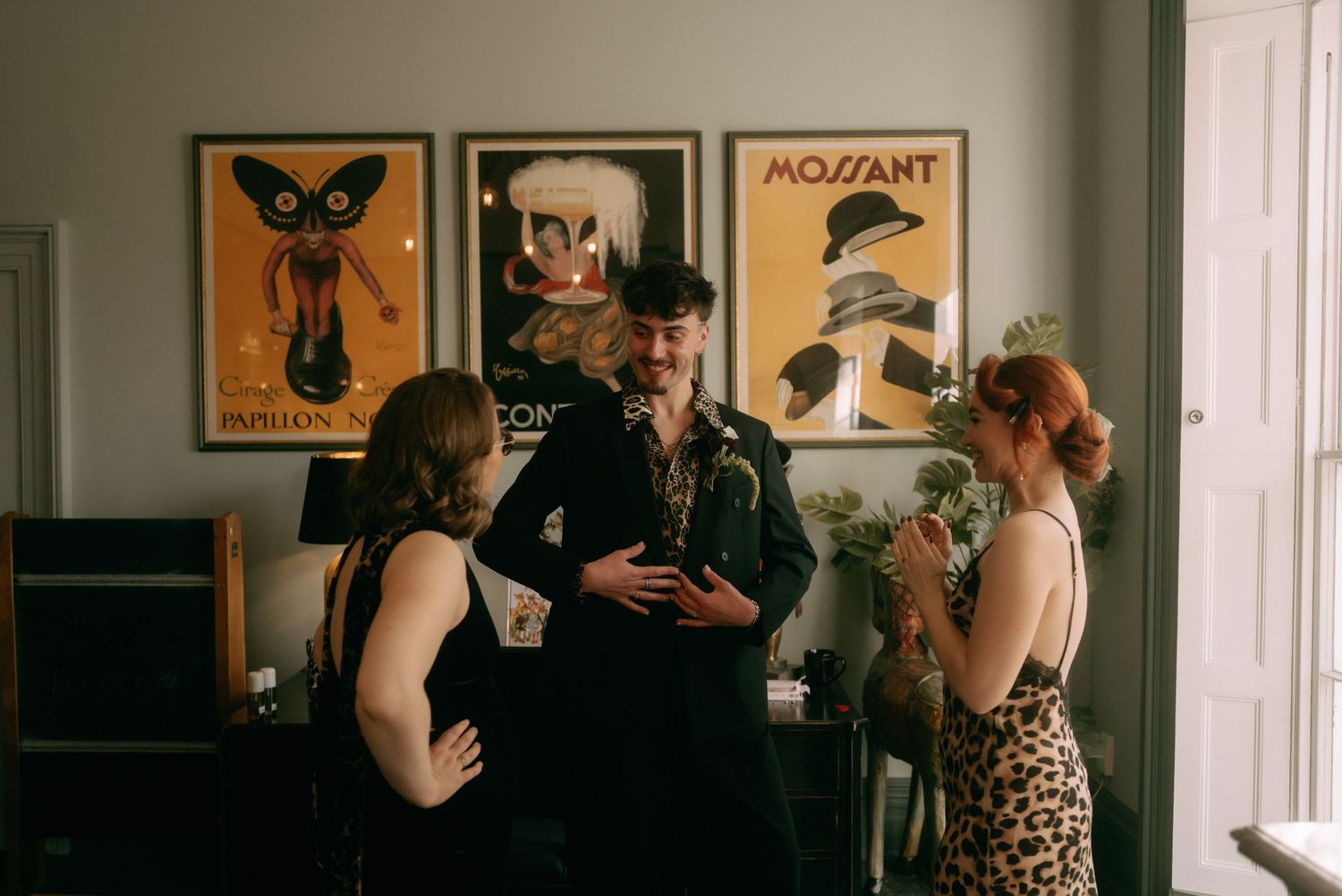 People dancing and socializing at a vintage-style party with butterfly artwork on the walls in a dimly lit room.