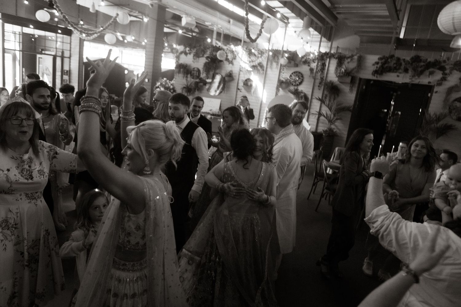Vintage black and white photo showing a crowded dance floor with partygoers in formal 1950s attire dancing under interior lighting.