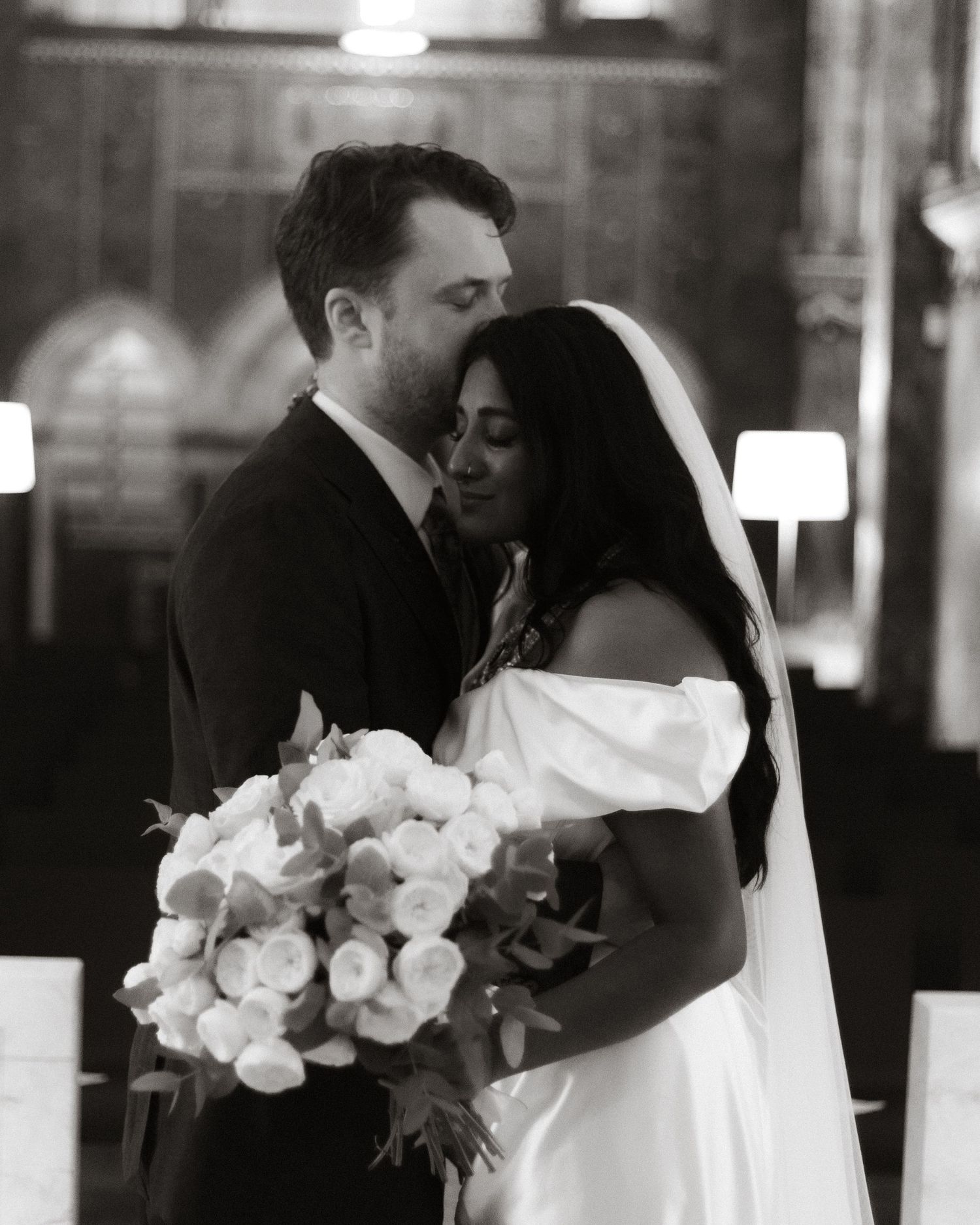 Black and white wedding ceremony photos showing intimate moments between a couple with white floral bouquets.