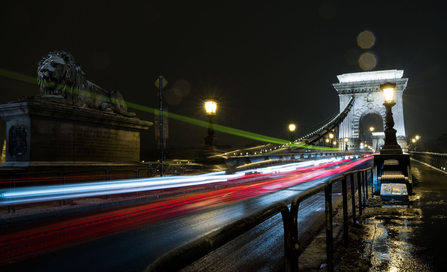 Long exposure night shot of Chain Bridge Budapest with light trails from traffic in rain.