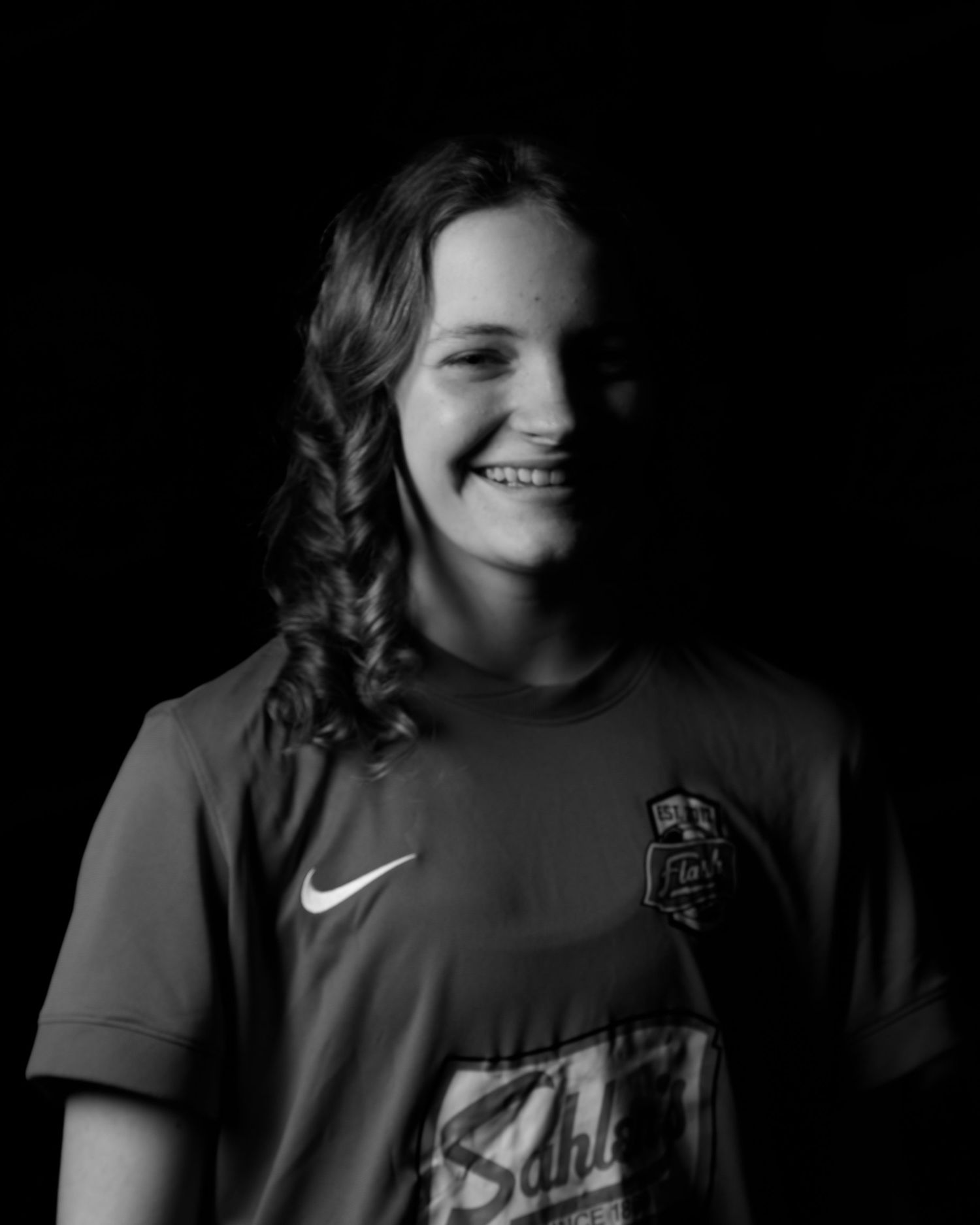 Smiling young female soccer player in Nike jersey poses for black and white portrait.
