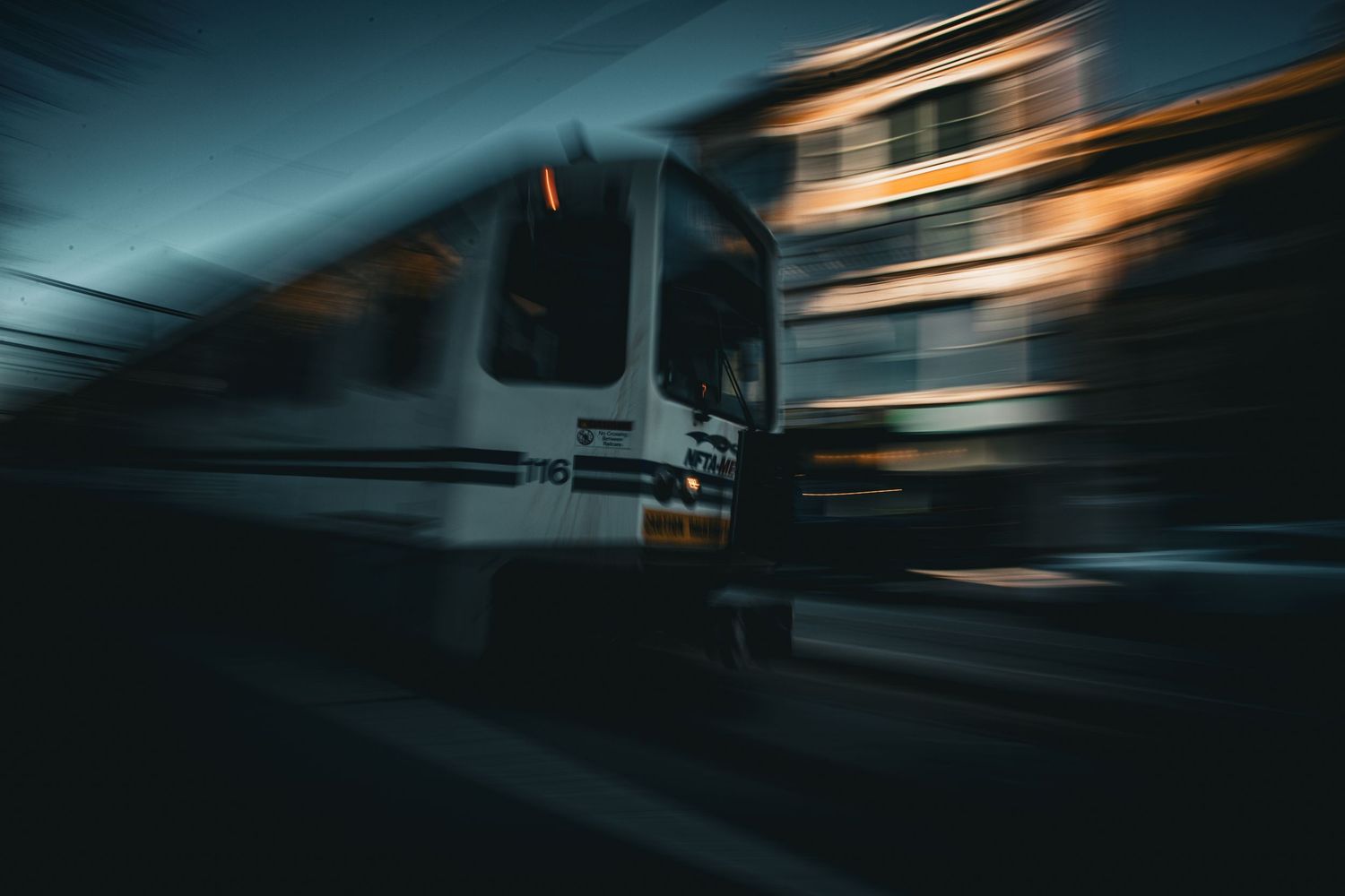 A train captured with motion blur speeding through the night in dramatic dark tones.