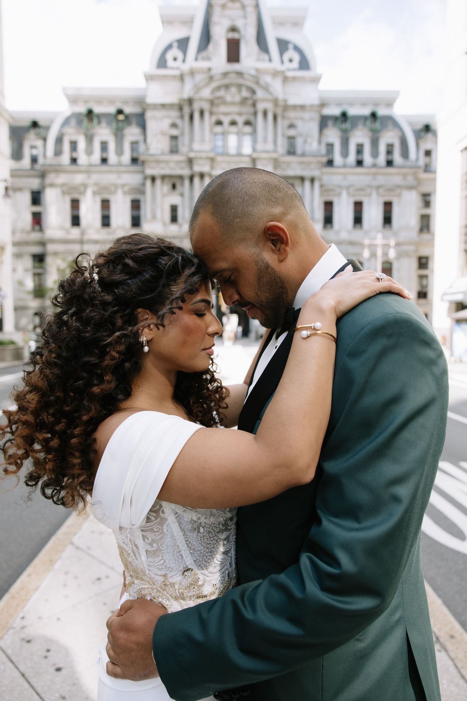 A bride and groom share a romantic embrace in front of Philadelphia City Hall on their wedding day.
