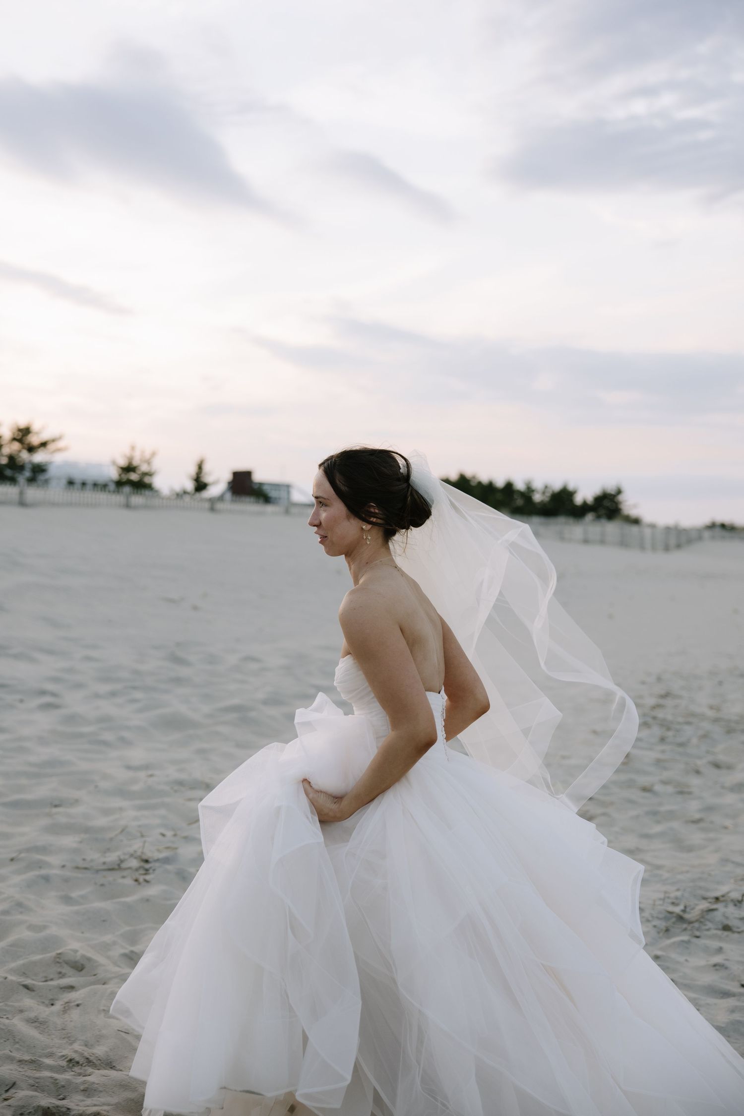 Romantic Bethany Beach wedding portrait of newlyweds walking along the shoreline at sunset in Delaware.