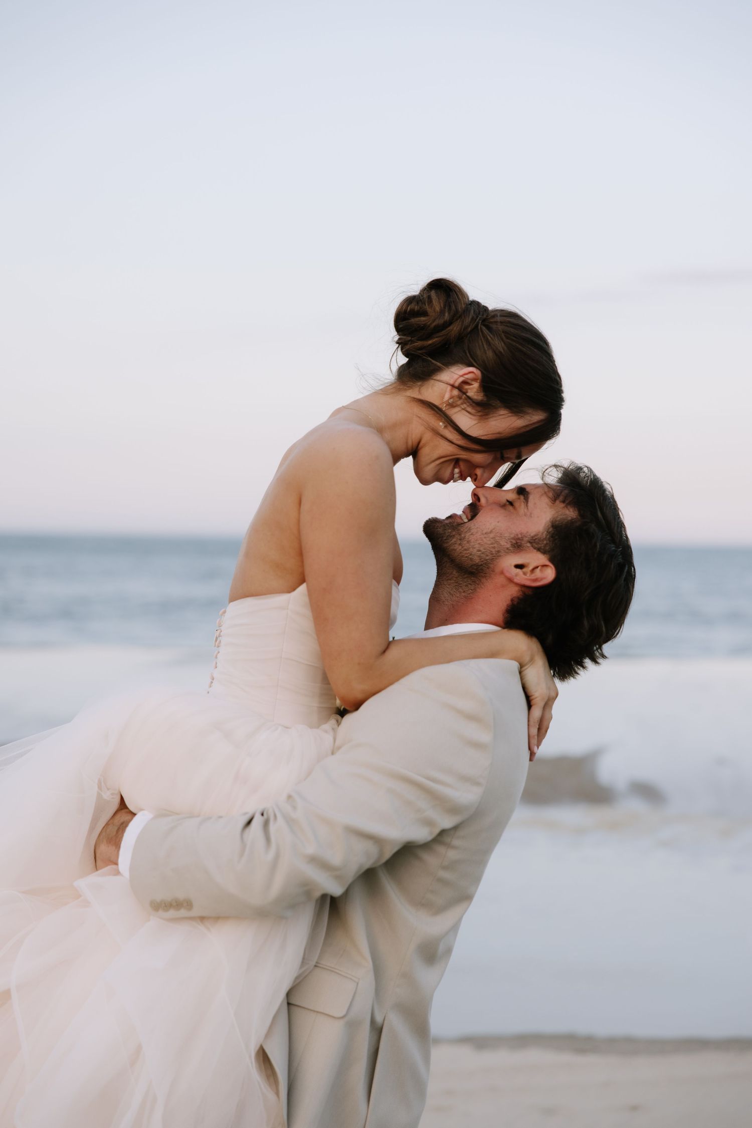 Romantic Bethany Beach wedding portrait of newlyweds walking along the shoreline at sunset in Delaware.