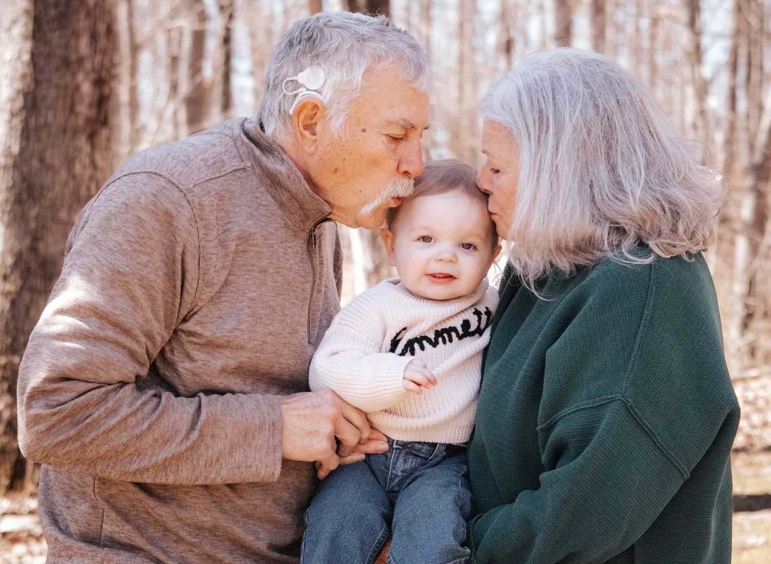 Grandparents kissing their grandson outdoors in a wooded setting during a family photo session in Troy, MO.