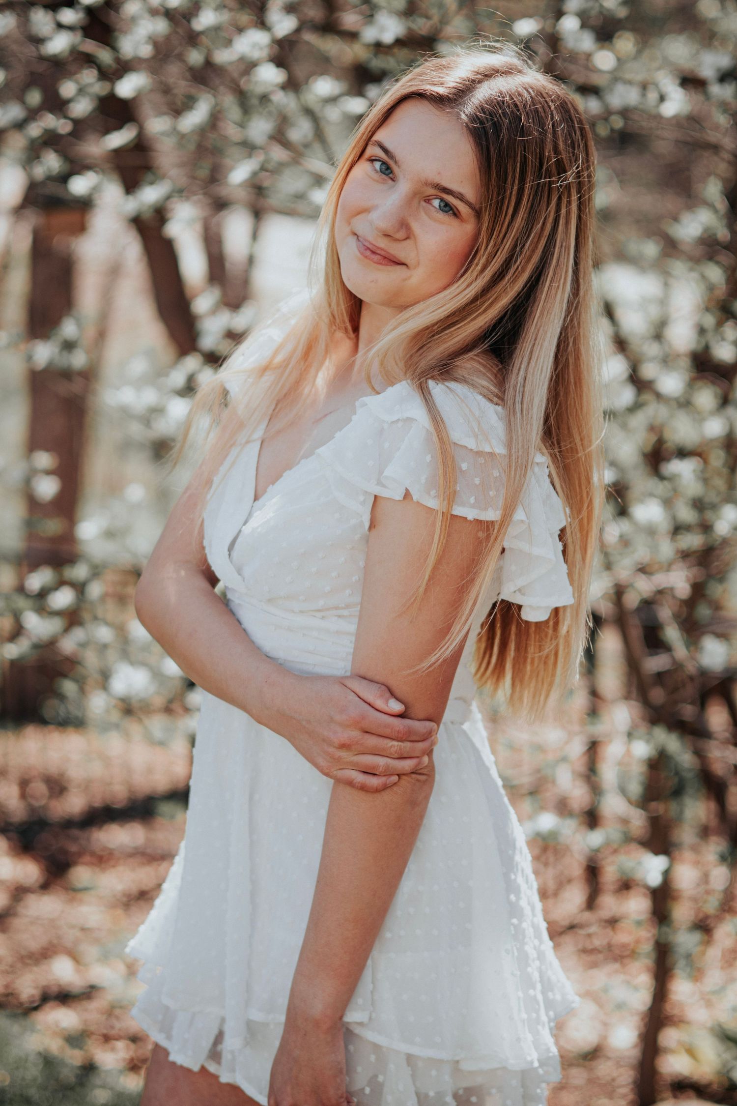 Senior girl posing in front of dogwood trees in O'Fallon, MO for her senior photo session.