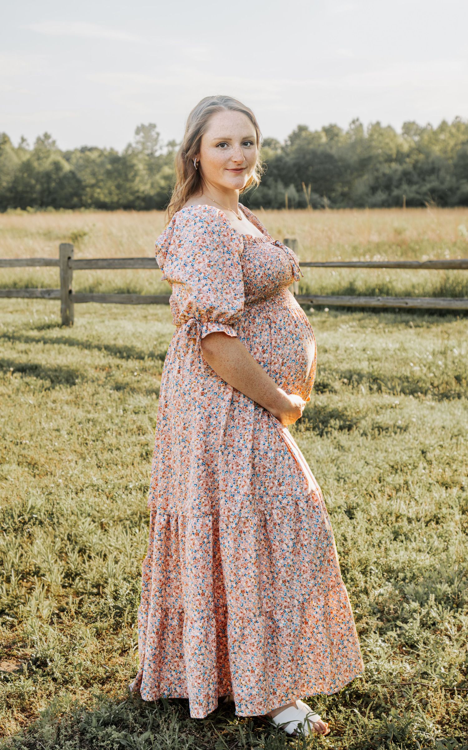 Pregnant woman in floral maxi dress posing outdoor at Indian Camp Creek Park in Foristell, MO