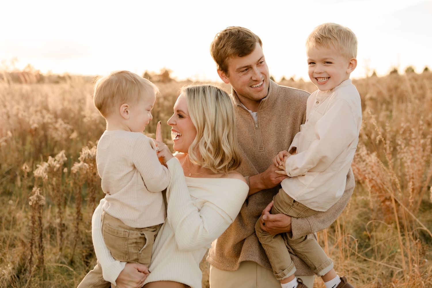 A happy family enjoying a warm sunset moment together in a golden field.