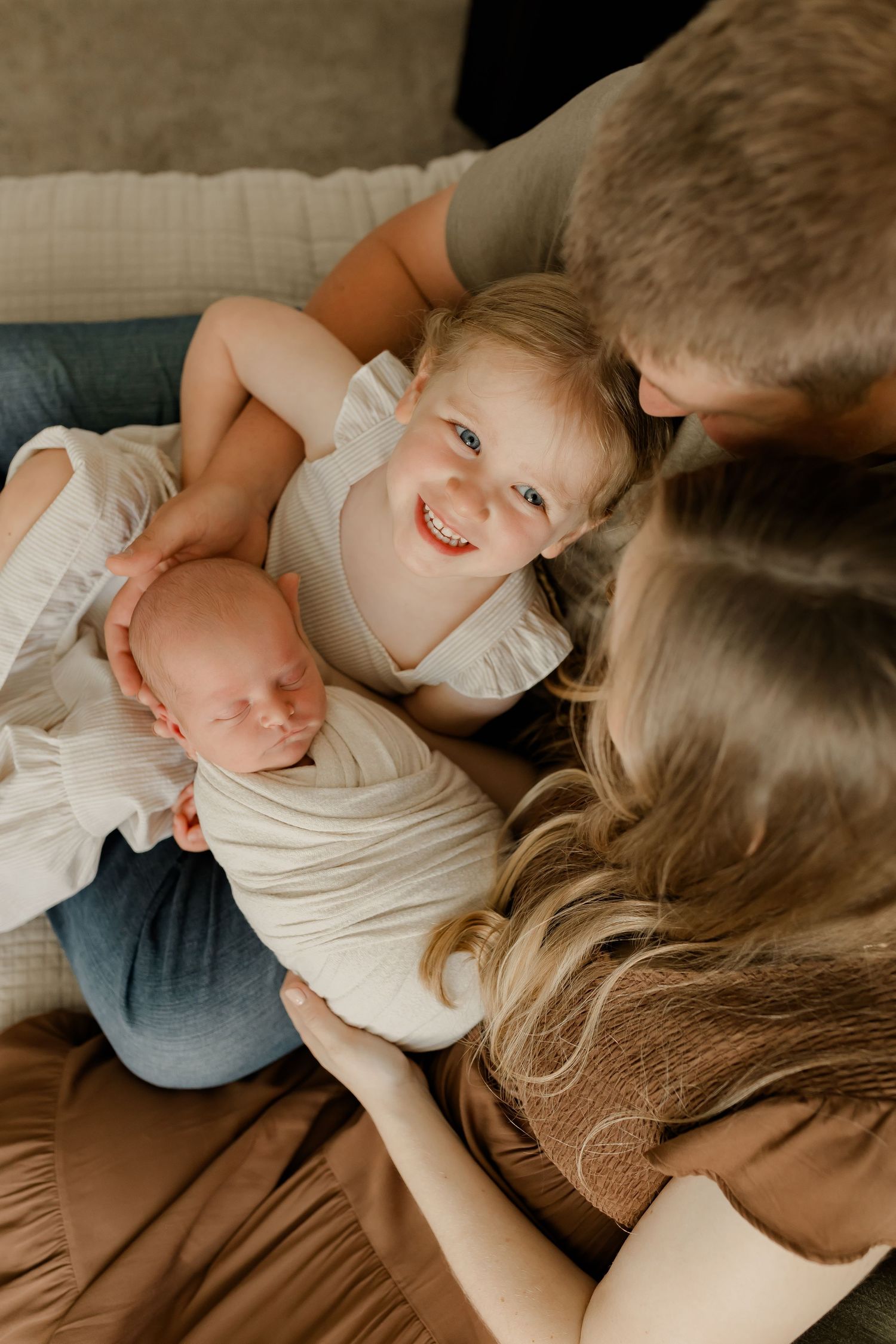 A warm family moment as they lovingly gather around a sleeping newborn baby.