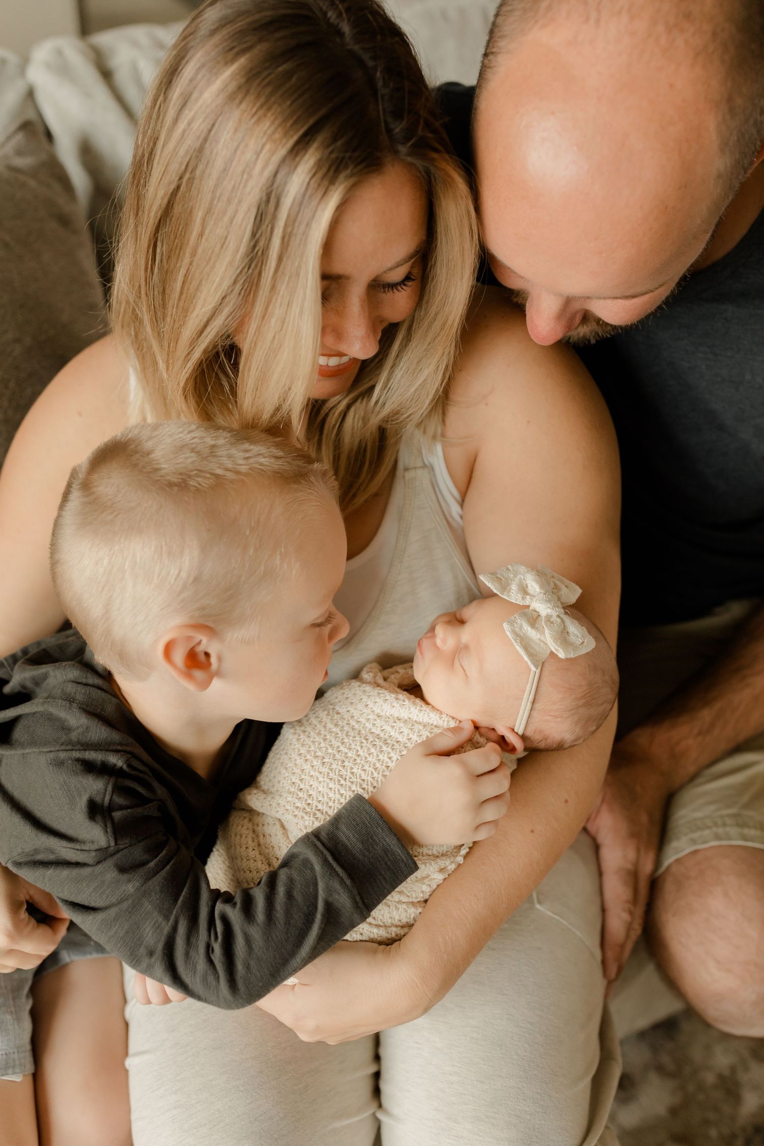 Family shares an intimate moment together while meeting their newborn baby at home.