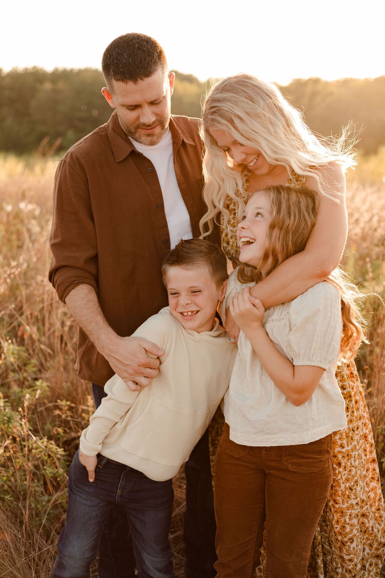 A family shares a joyful moment together in a sunlit field during golden hour.