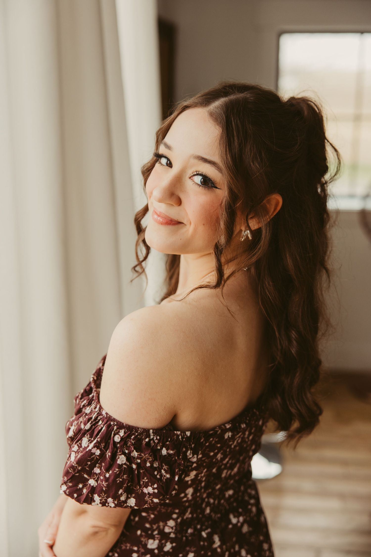 A warm portrait in burgundy floral dress with soft lighting and natural curls styled romantically.