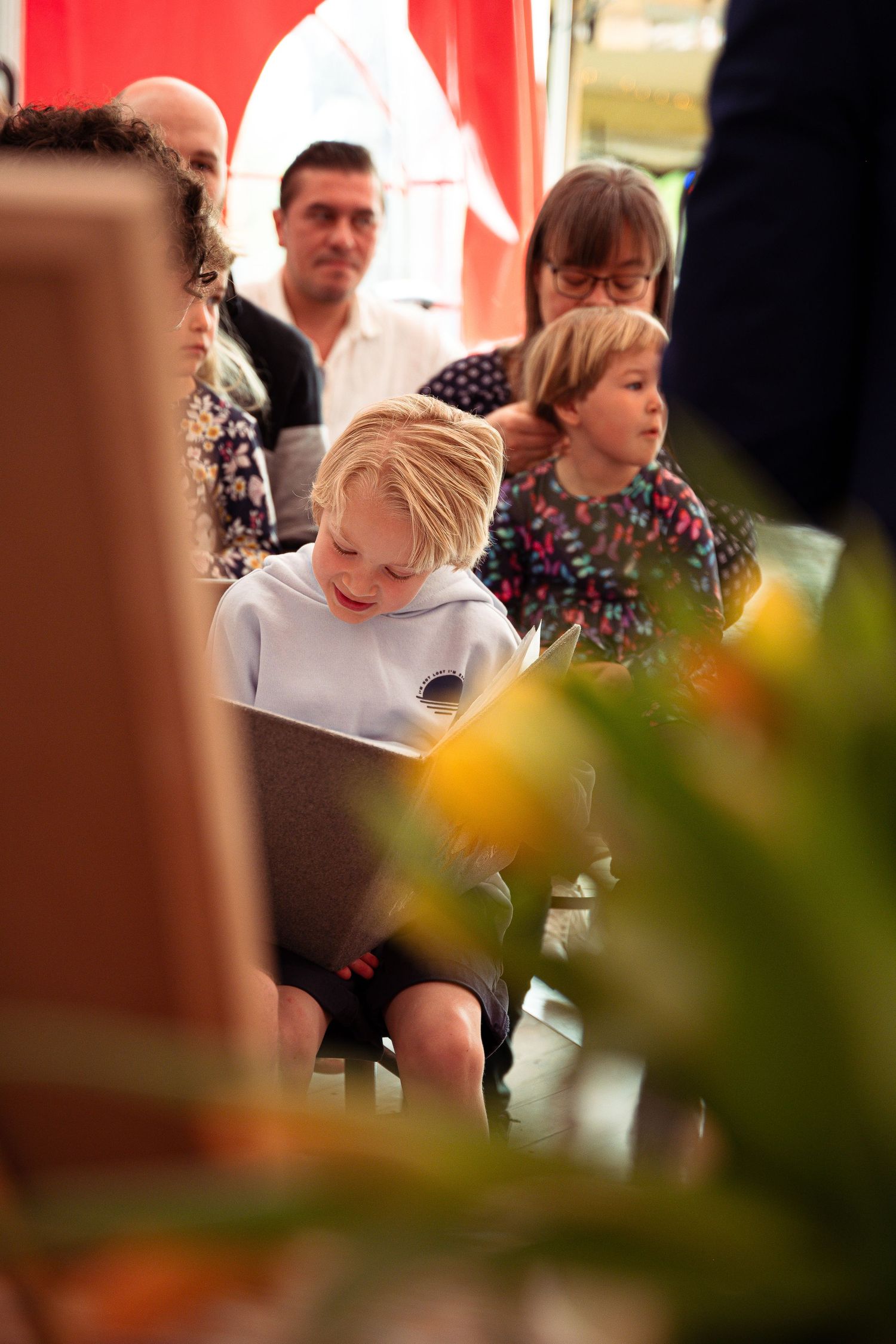 Blondharig jongentje dat in een boek voorleest tijdens een doopfeest