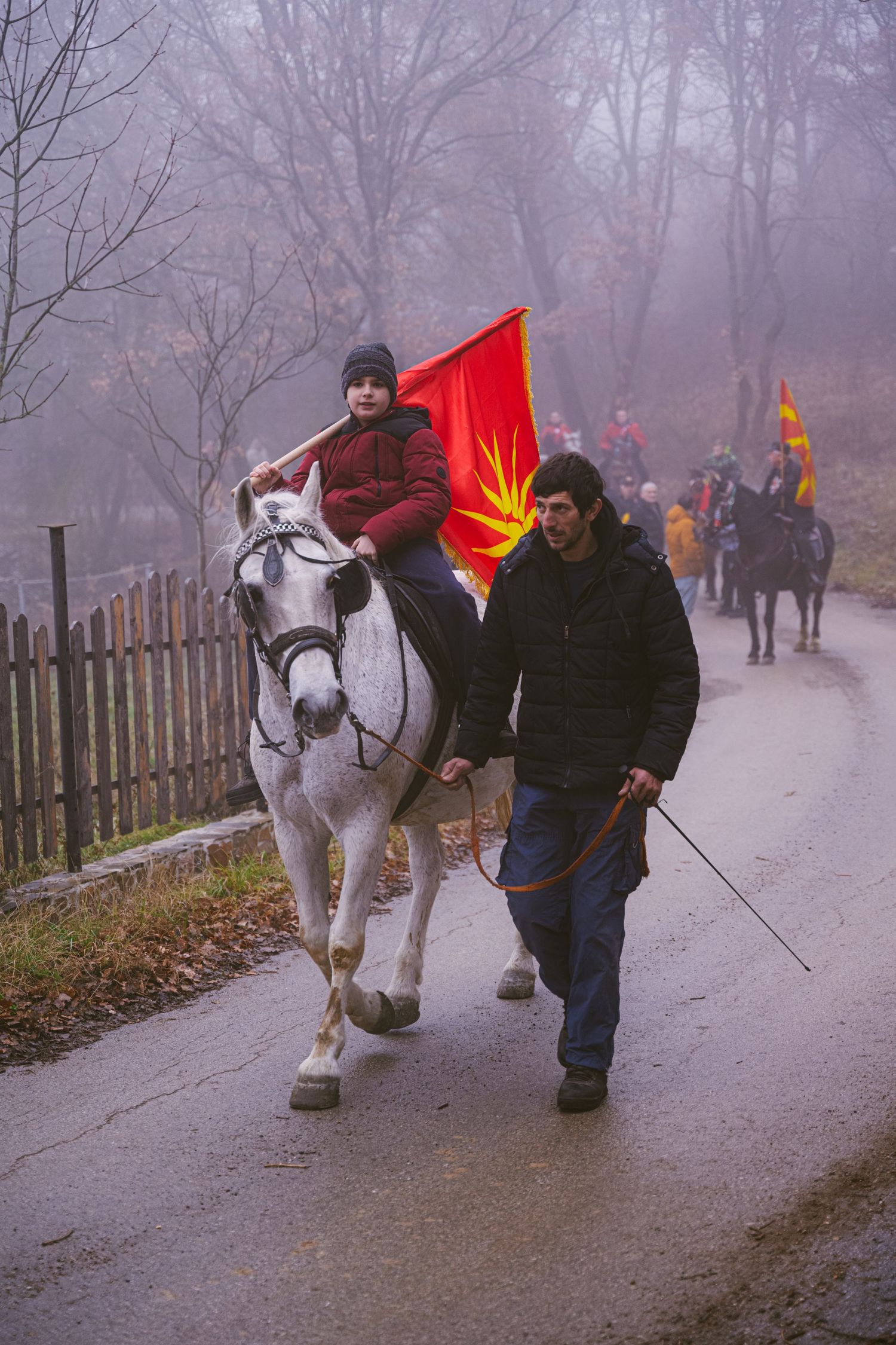 Een jongen op een paard met een man naast, macedonische vlag