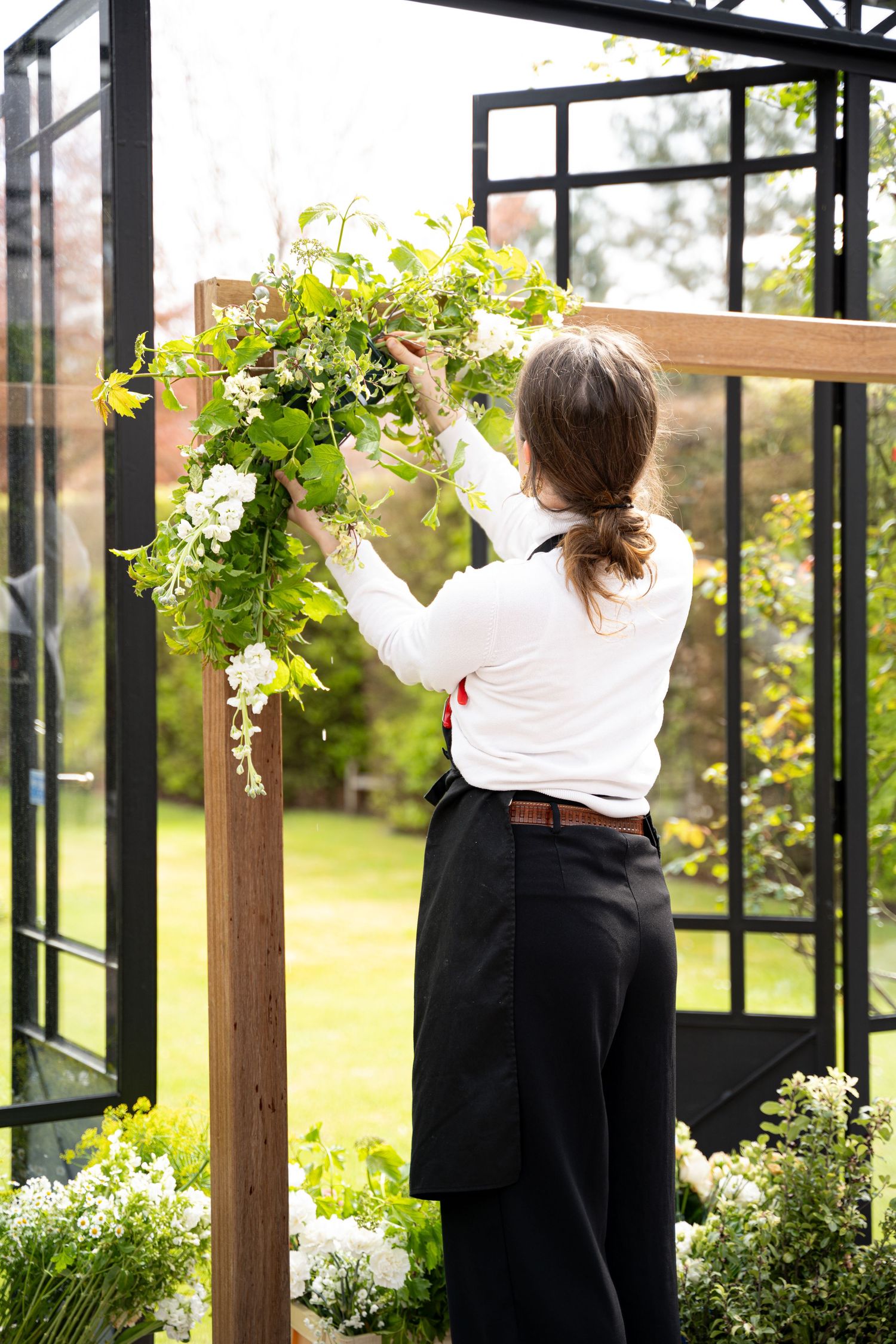 Een kleurenfoto van een vrouw die een bloemenstuk aan het maken is voor een huwelijk