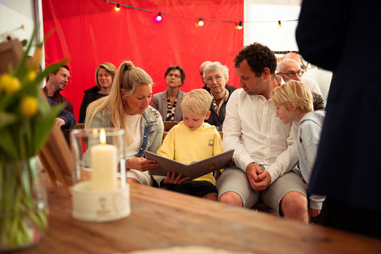 Familie dat samen in een voorleesboek kijkt tijdens een doopfeest