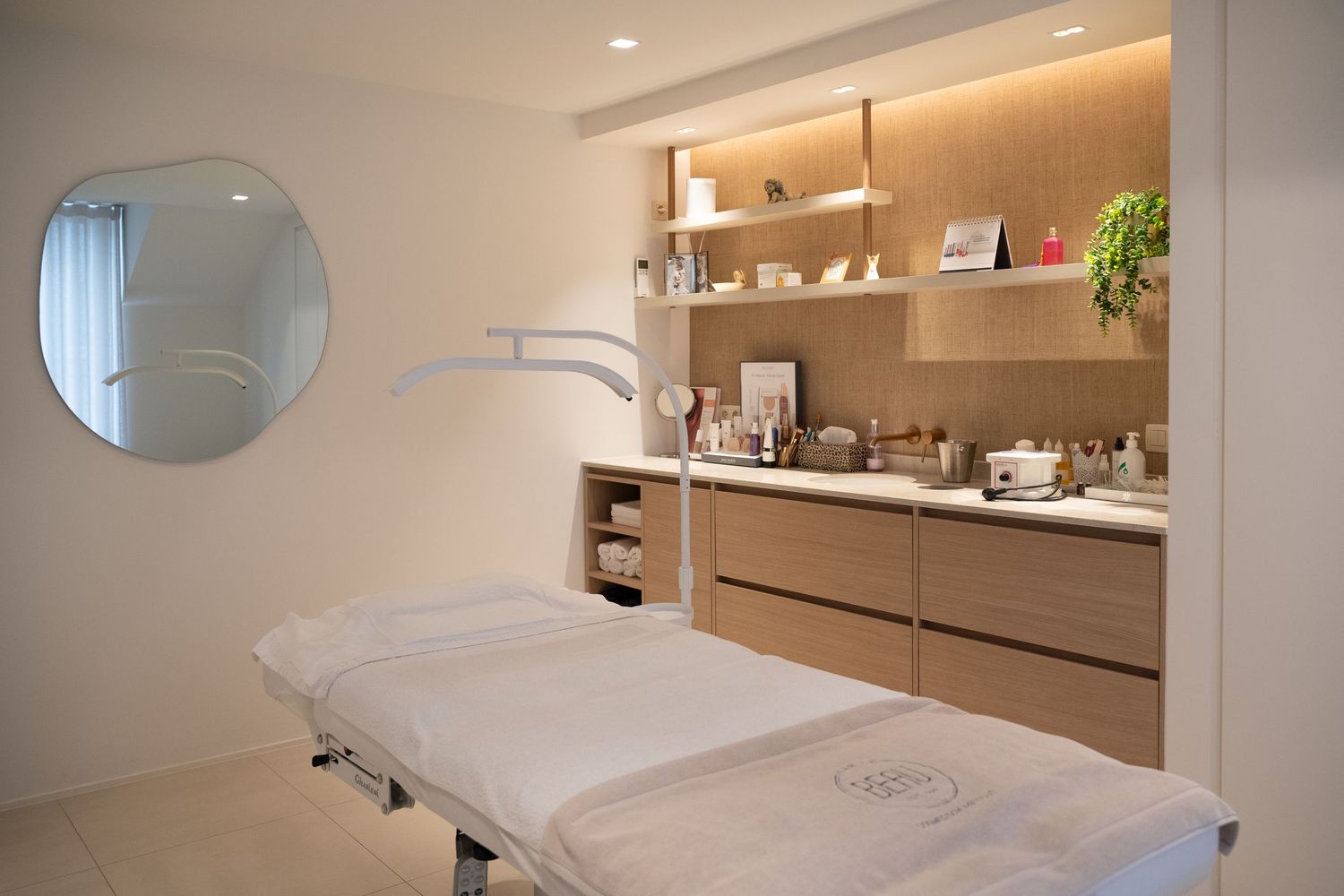 Een kleurenfoto van een zachtkleurig interieur van een schoonheidssalon, waar een behandeltafel staat.
