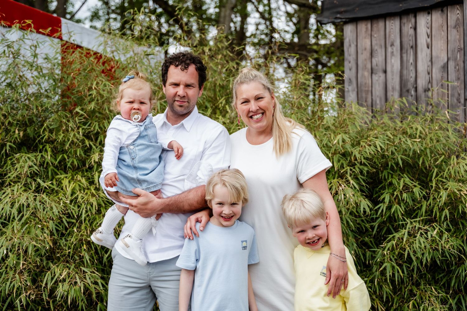 Een kleurfamiliefoto van twee ouders met hun drie kinderen